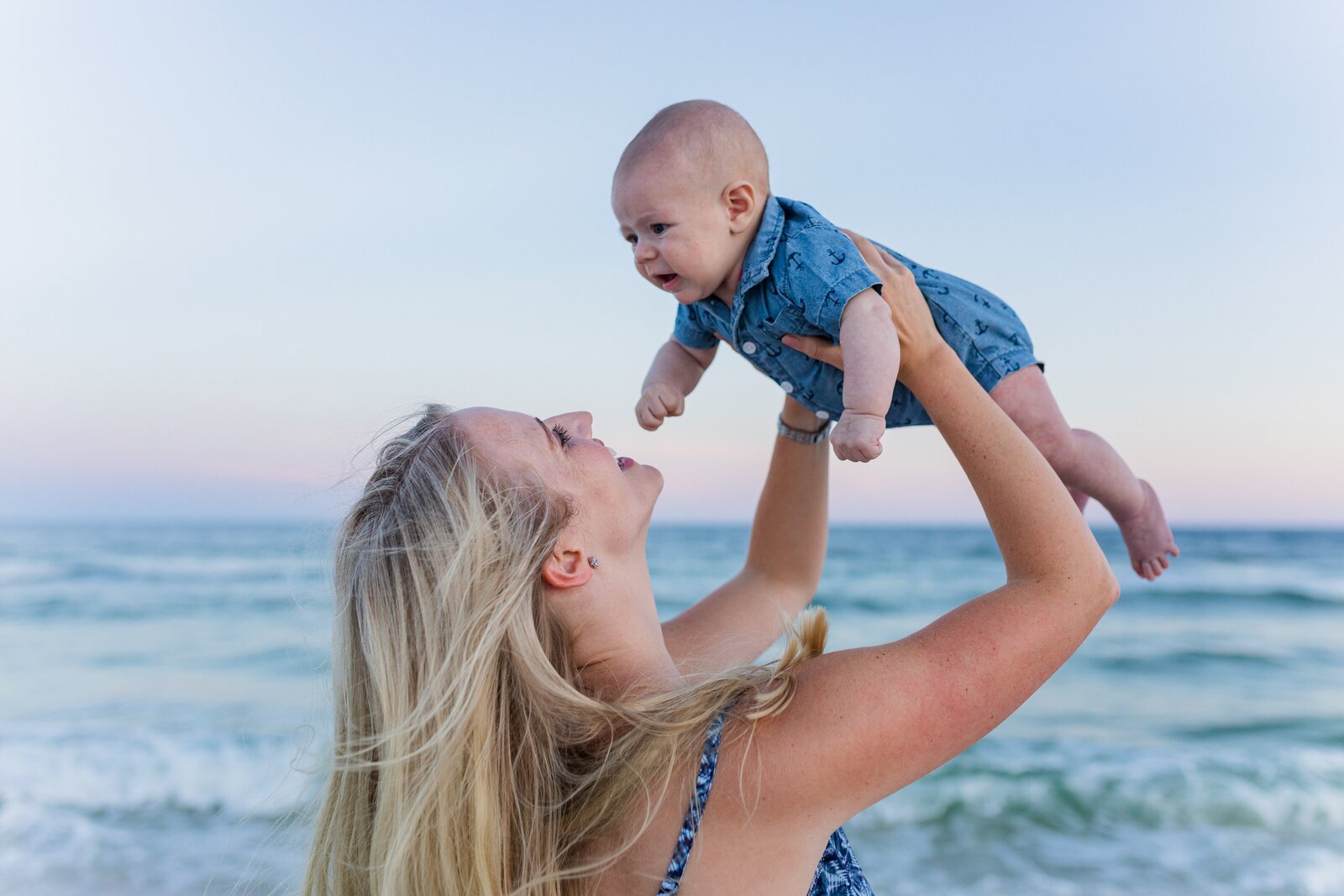 Mother holding son up to sky on Pensacola Beach