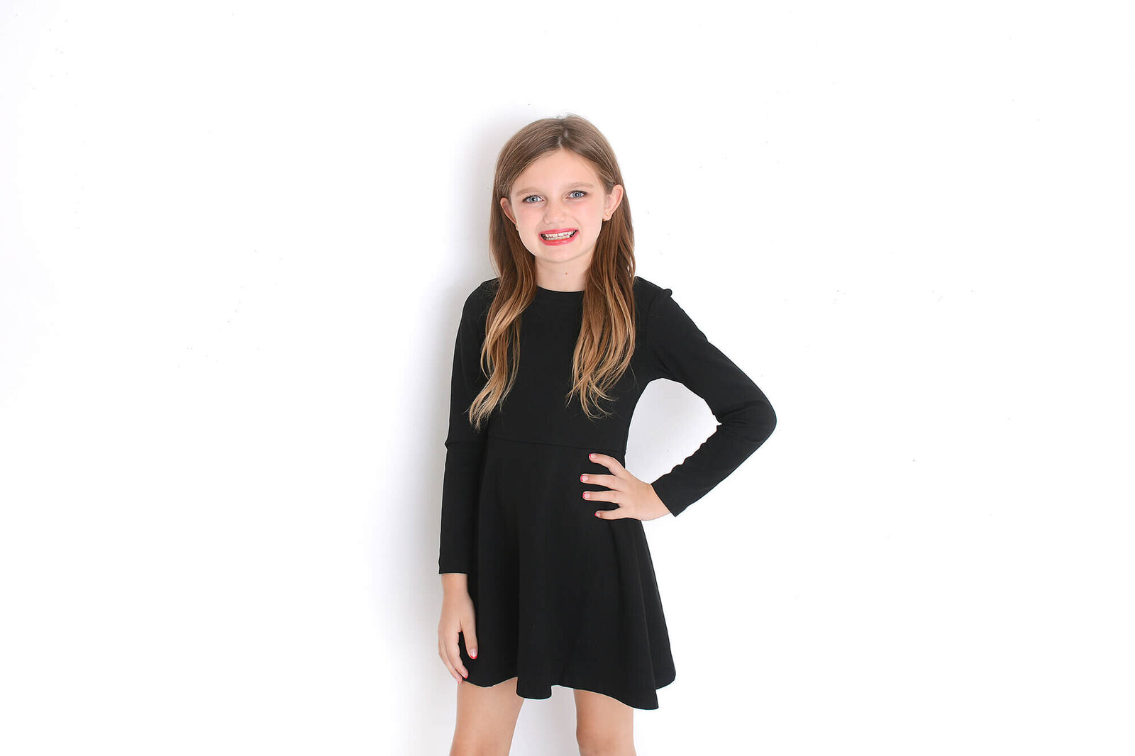 a girl smiles at the camera in front of a white background