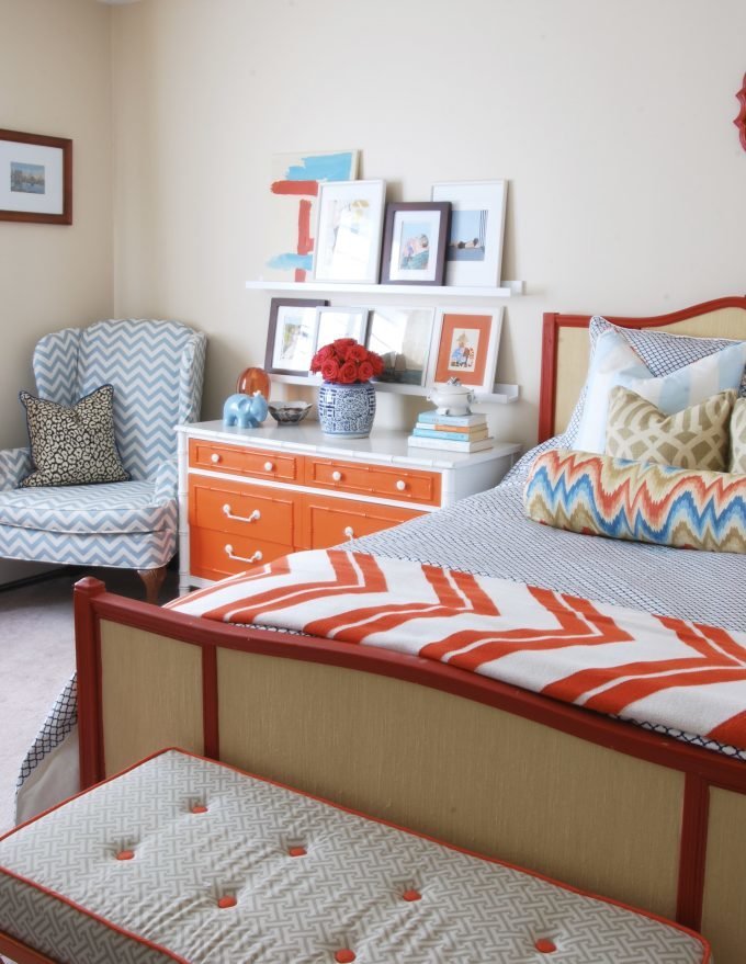 A colorful bedroom with a bed, dresser, chair, and accessories.