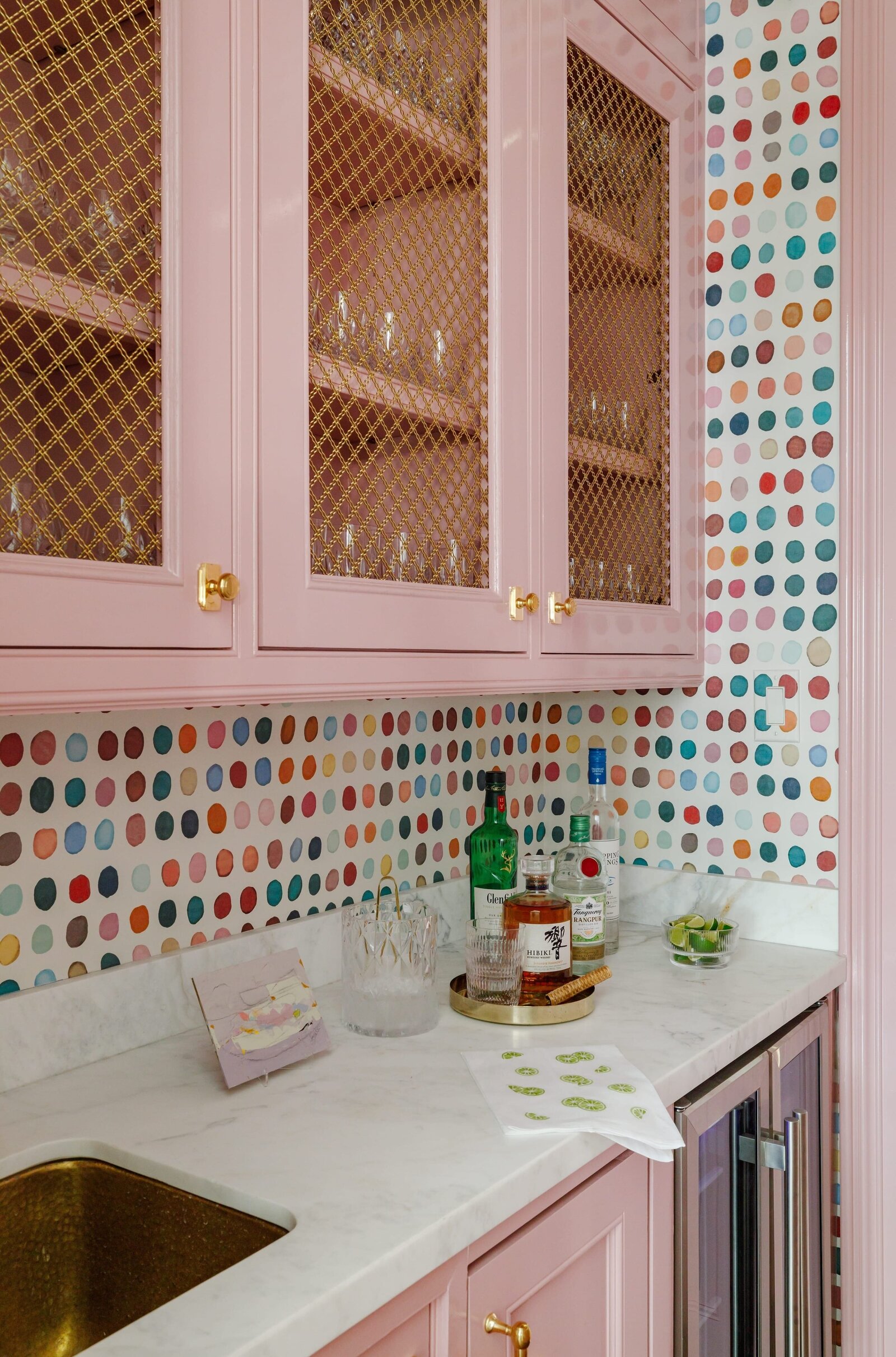 vision and hammer bar counter with colorful dotted wallpaper and pink cabinets