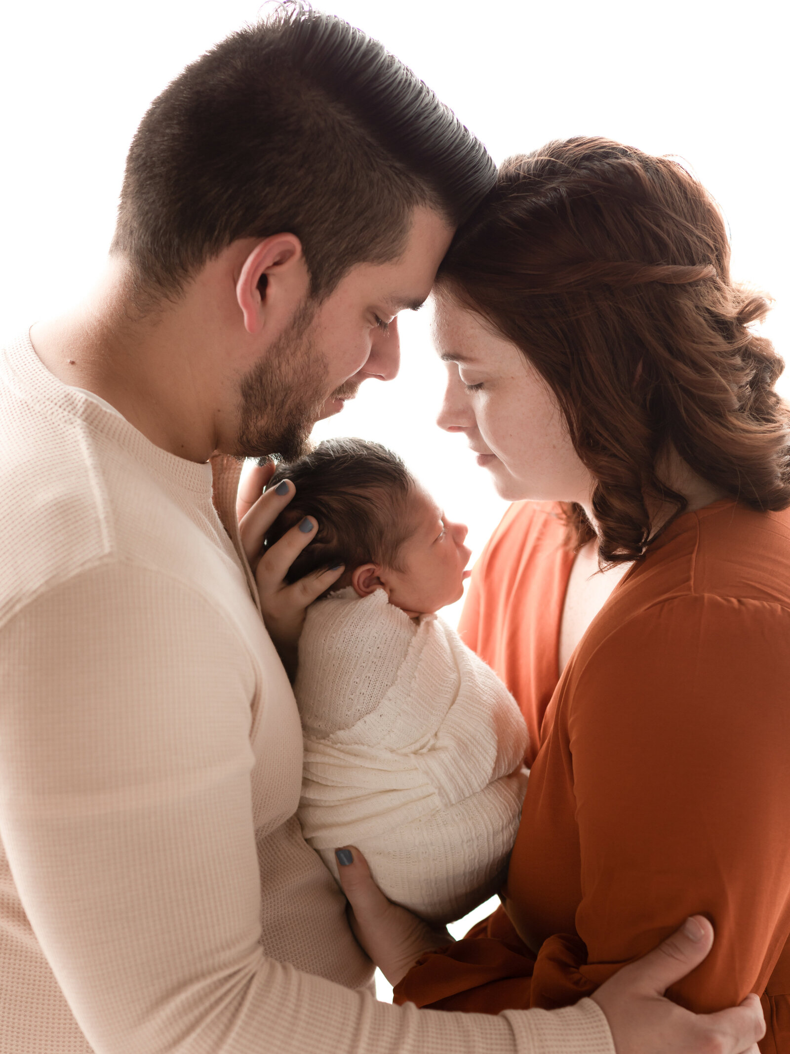 mom and dad holding newborn baby boy for photoshoot