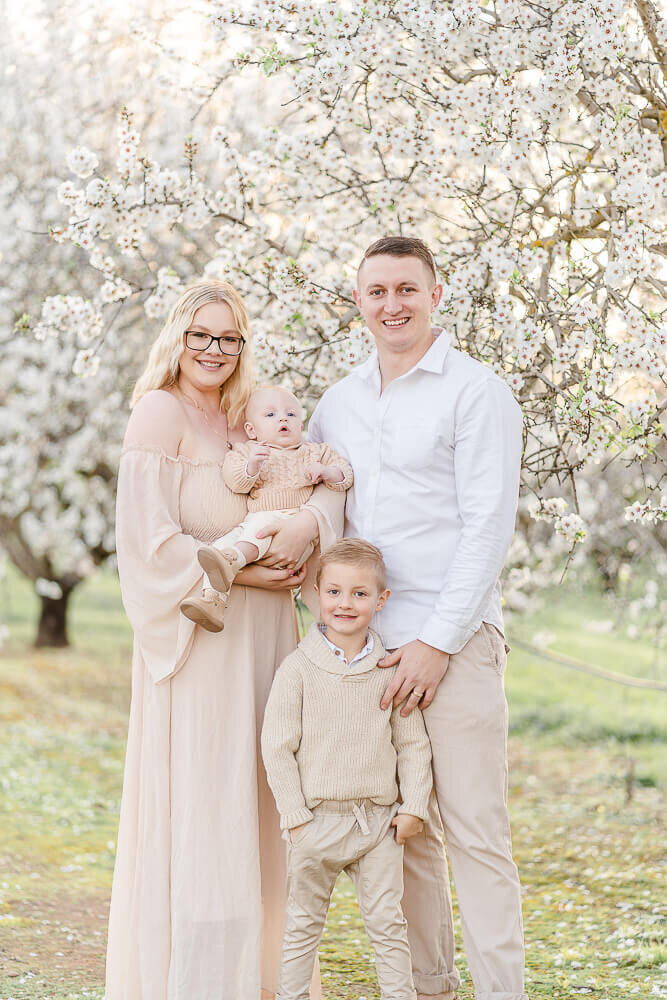 gorgeous family in neutral outfits smiling at camera in the flowers in brisbane sunset