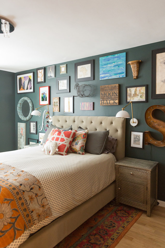 A bed with a tufted headboard and gallery wall.
