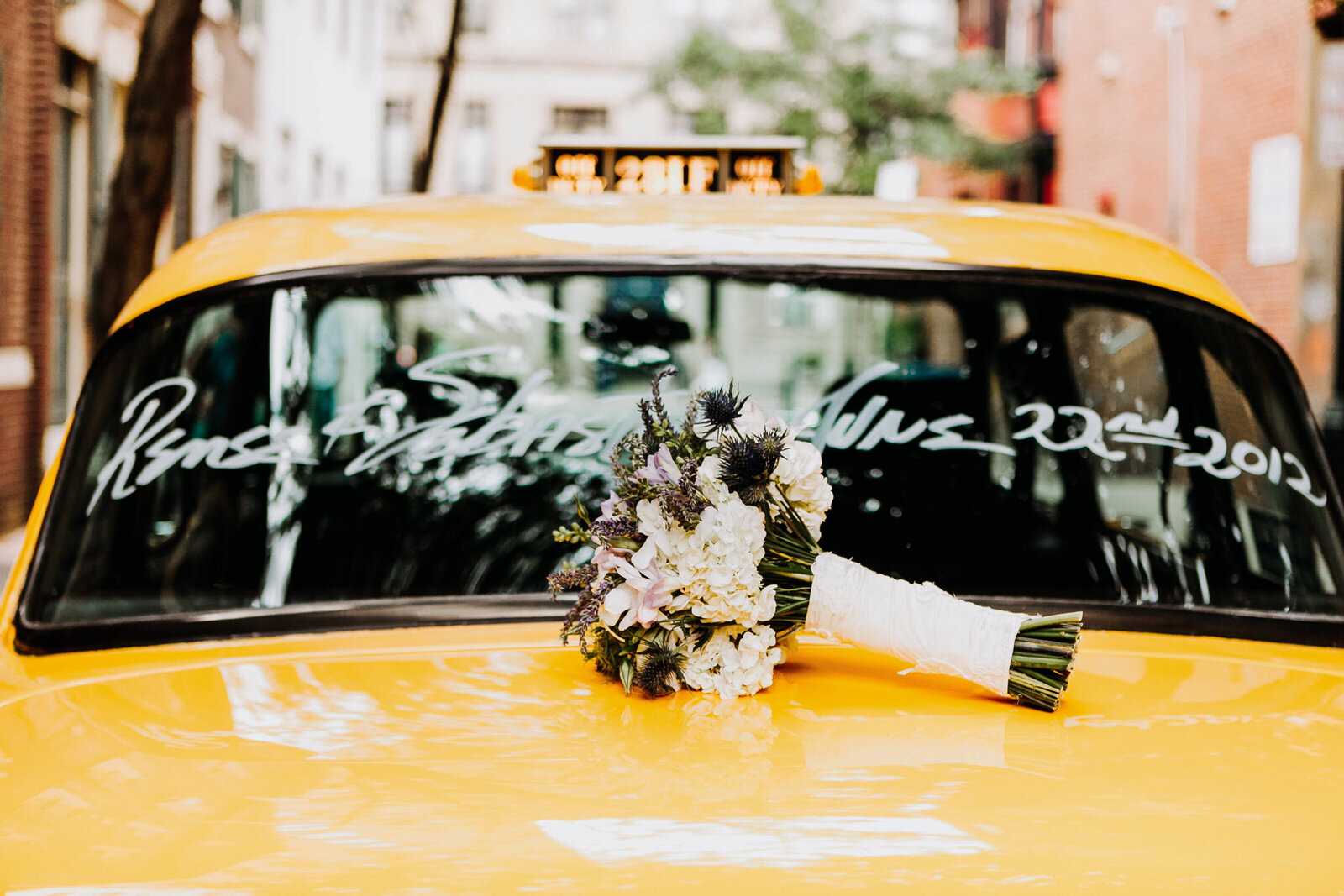 bridal bouquet on yellow taxi cab