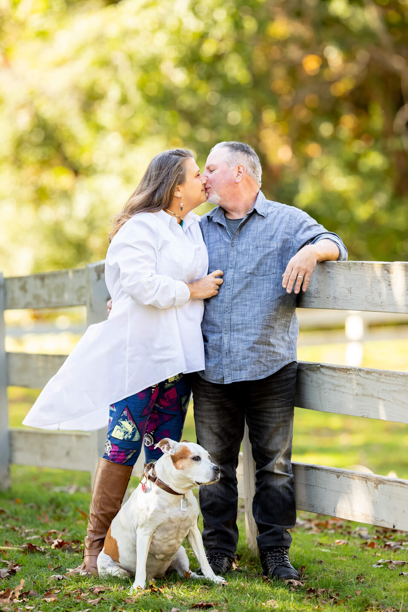 Couples photography of male and female adults sharing a kiss while standing with their dog