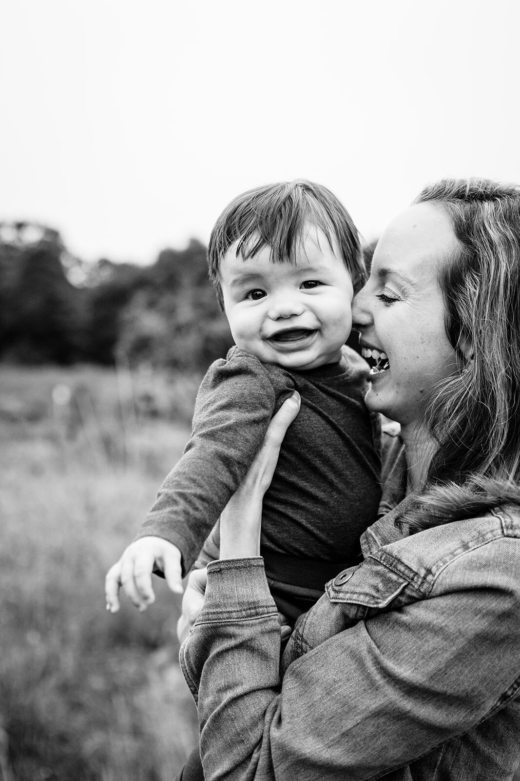 black and white image of mom snuggling baby boy during family pictures