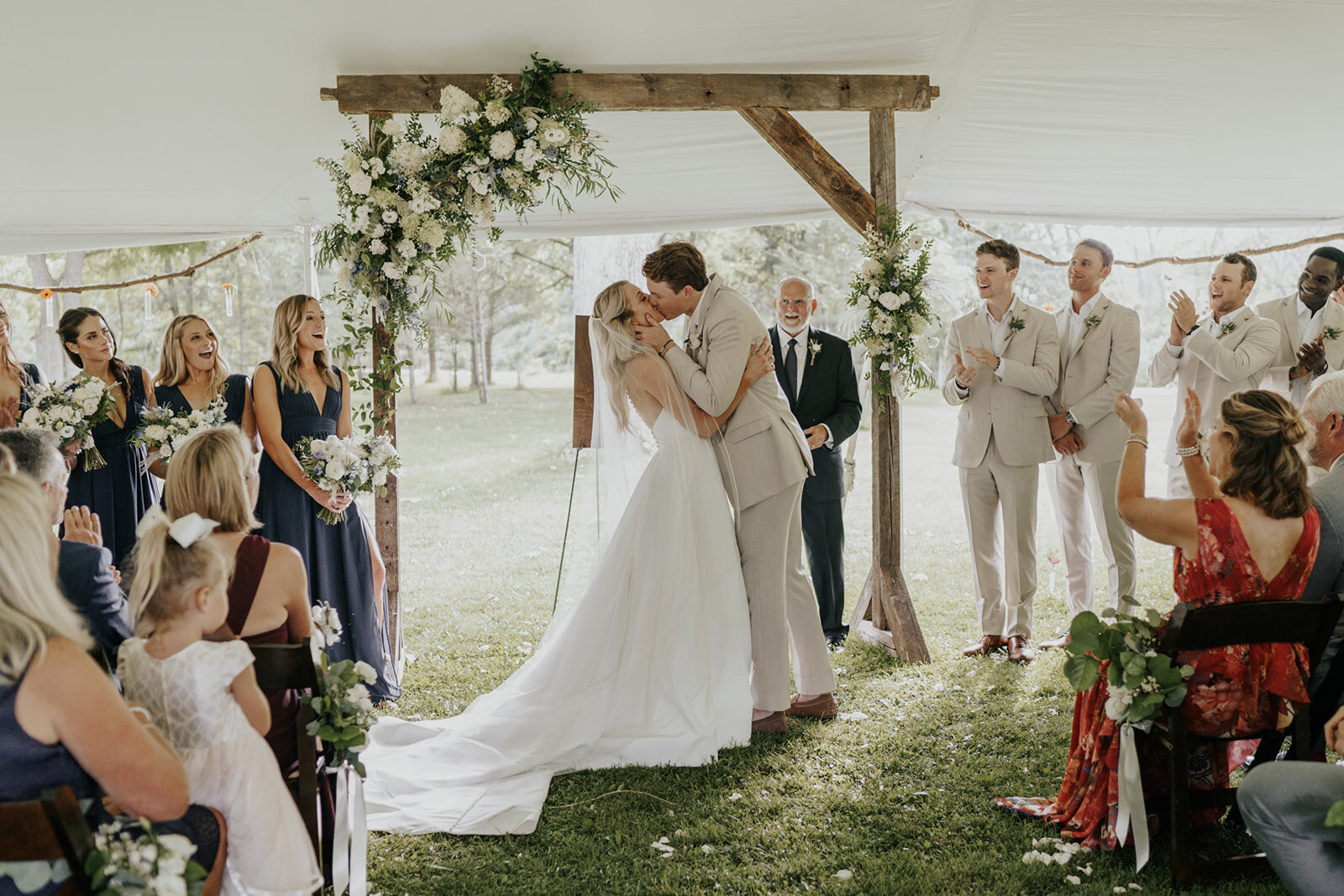 bride and groom kissinf under the arch in an indoor wedding ceremony at barnwood events in madison, winconsin.