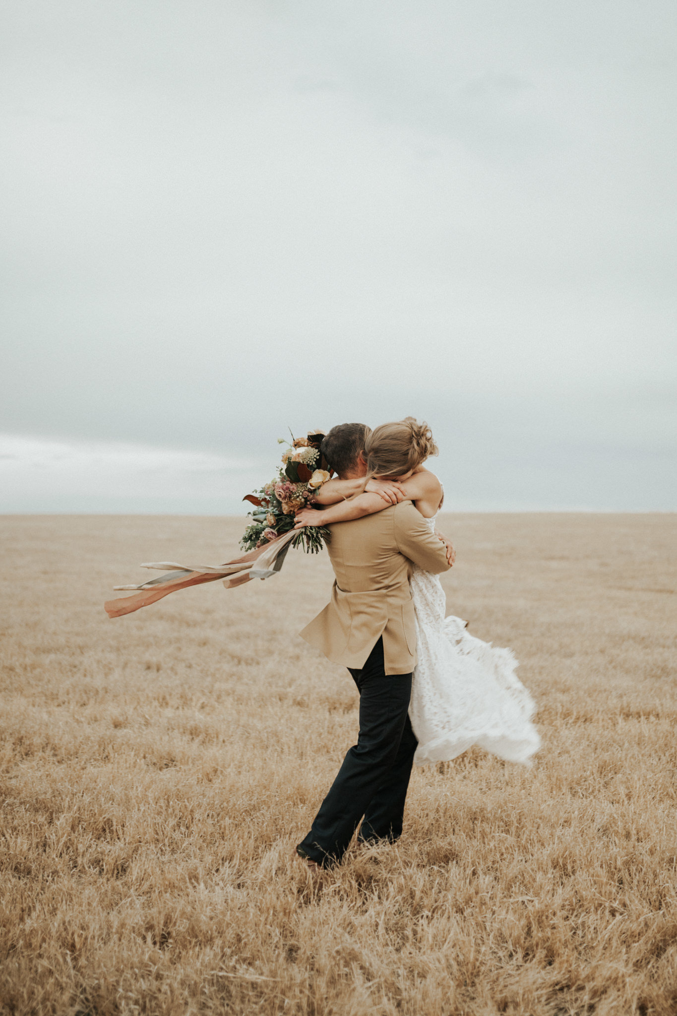 A bride and groom photo in an open field at sunset.
