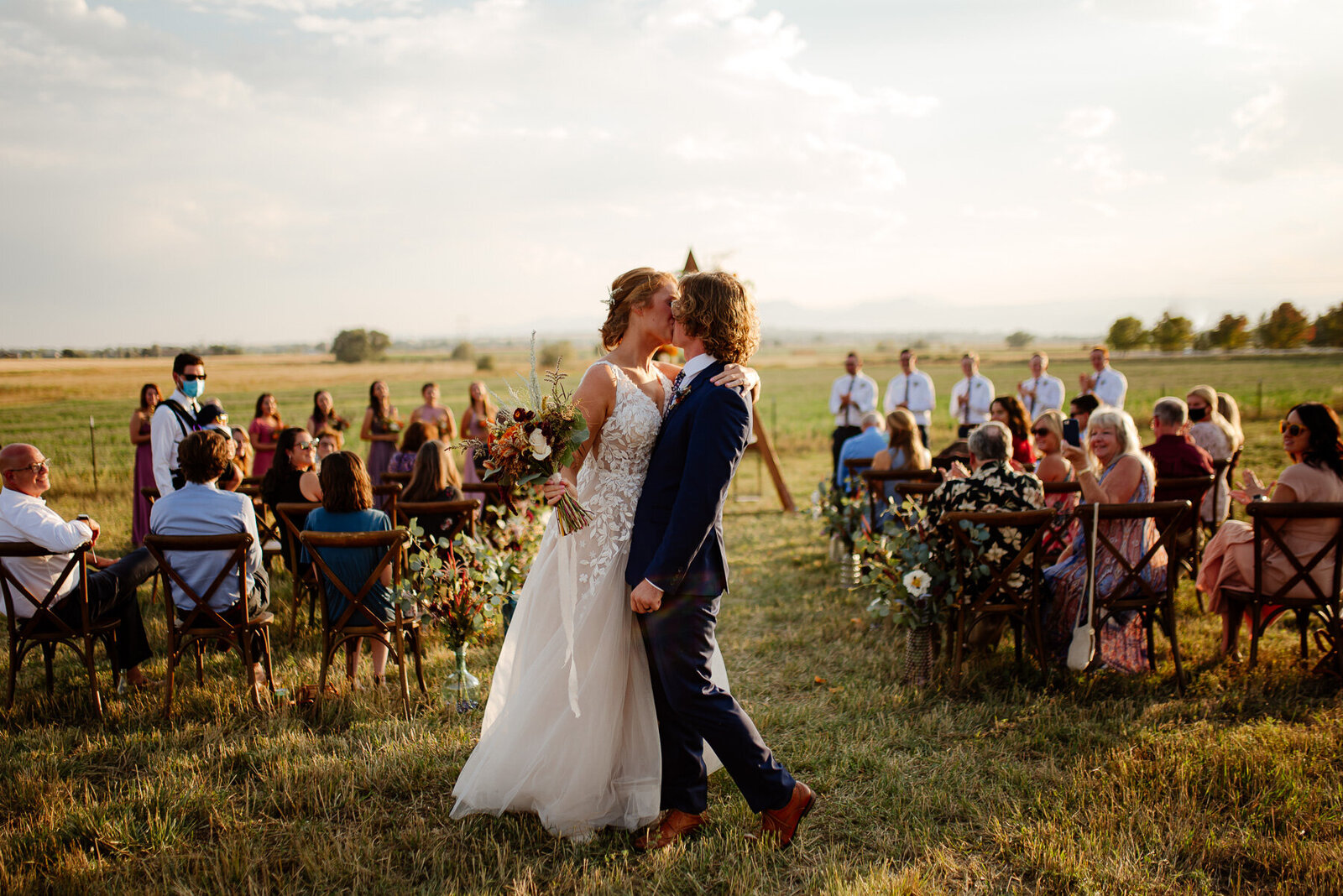Destination wedding at a farm in a field, first kiss by bride and groom.