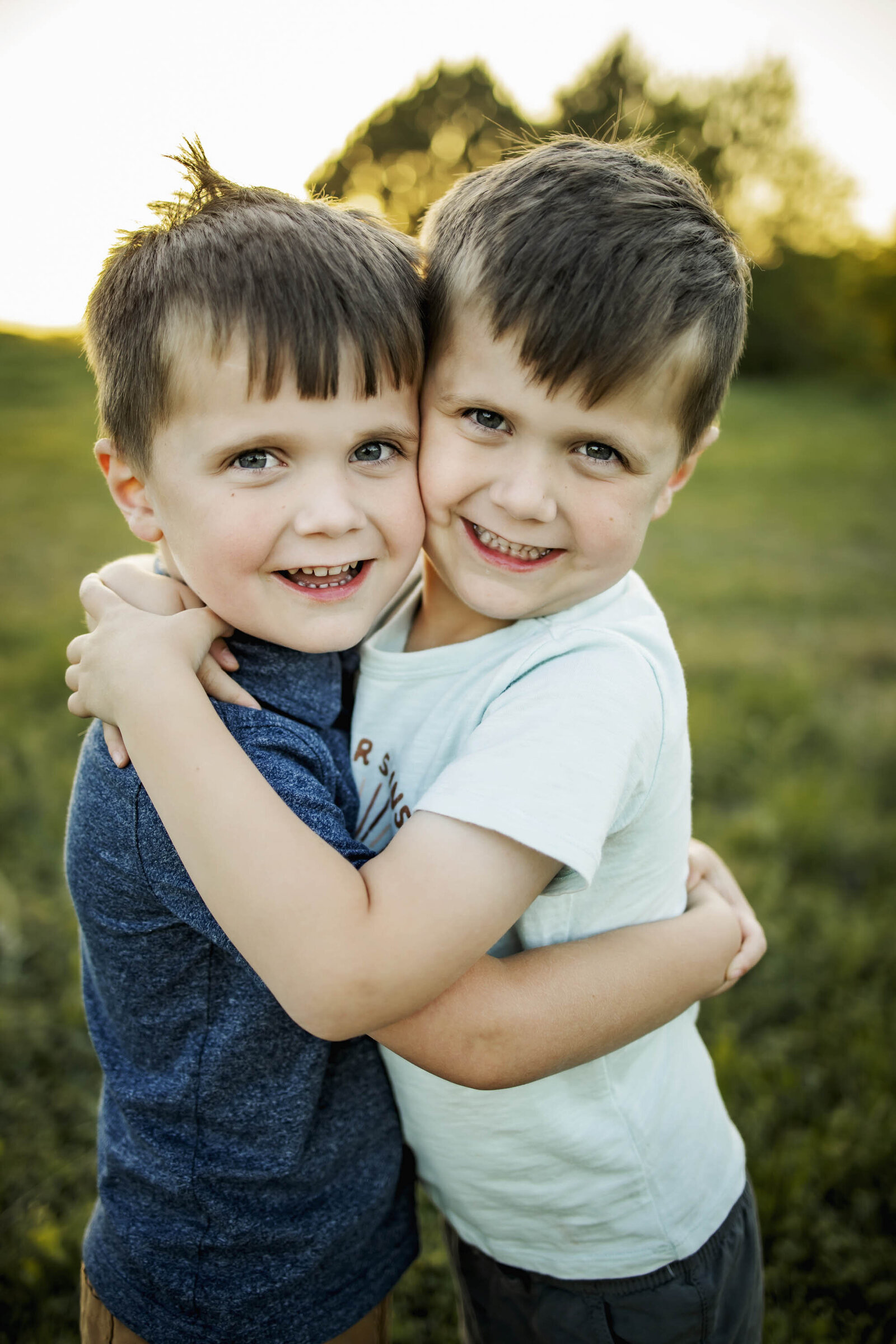 twin brothers embrace and smile in the park in Plano texas