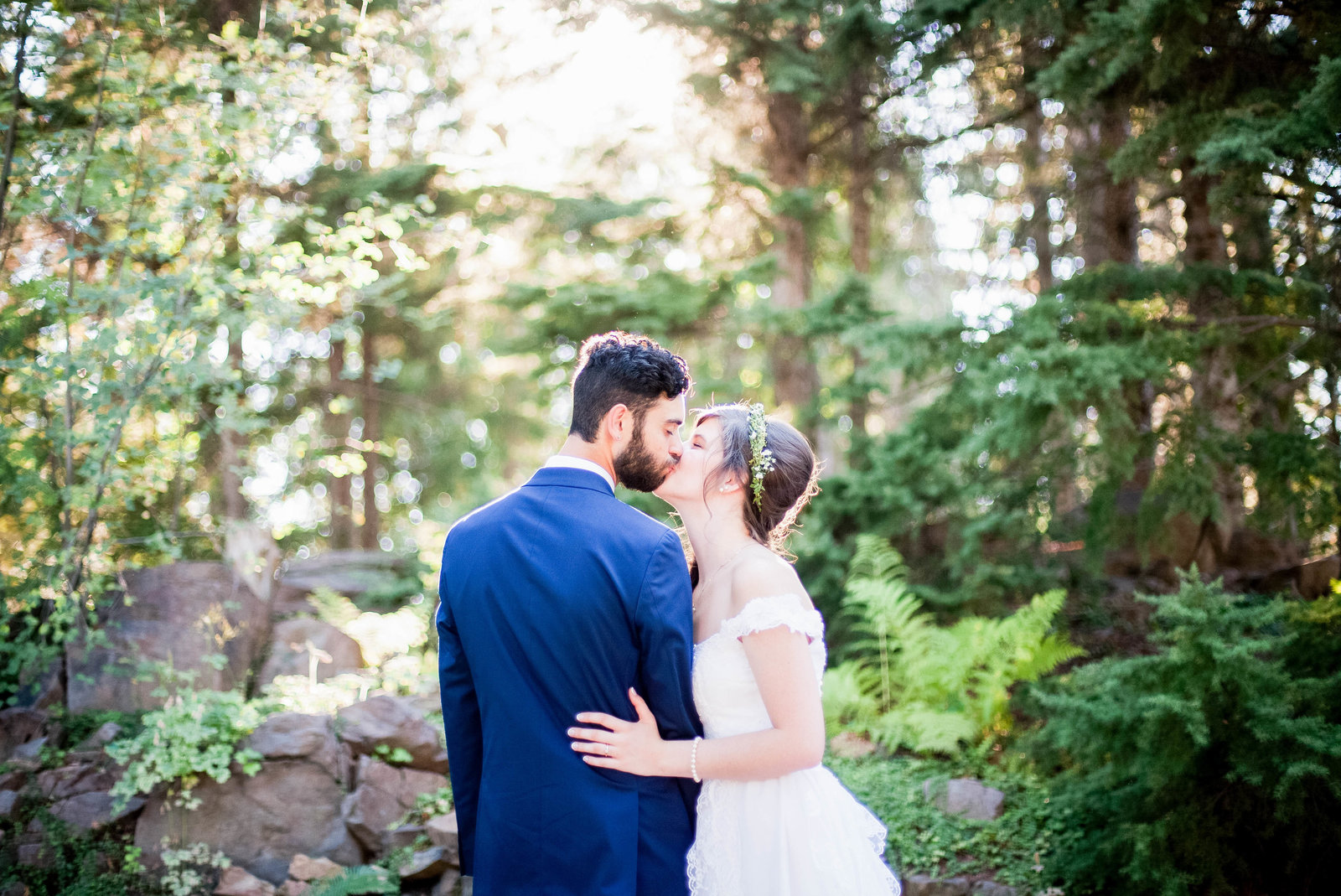 A bride and groom kissing in a forest.