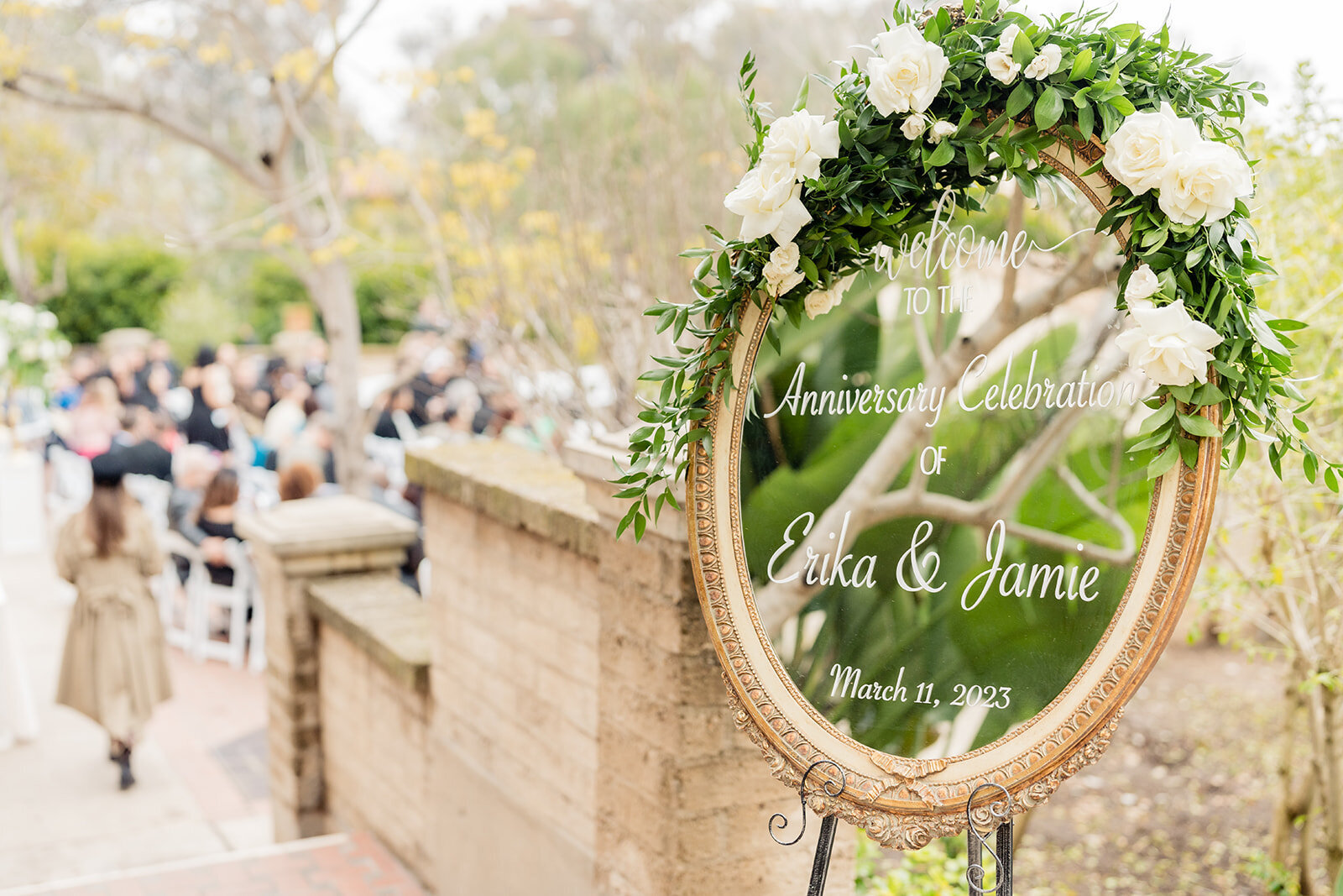 A golden rimmed mirror welcome sign at a wedding ceremony.