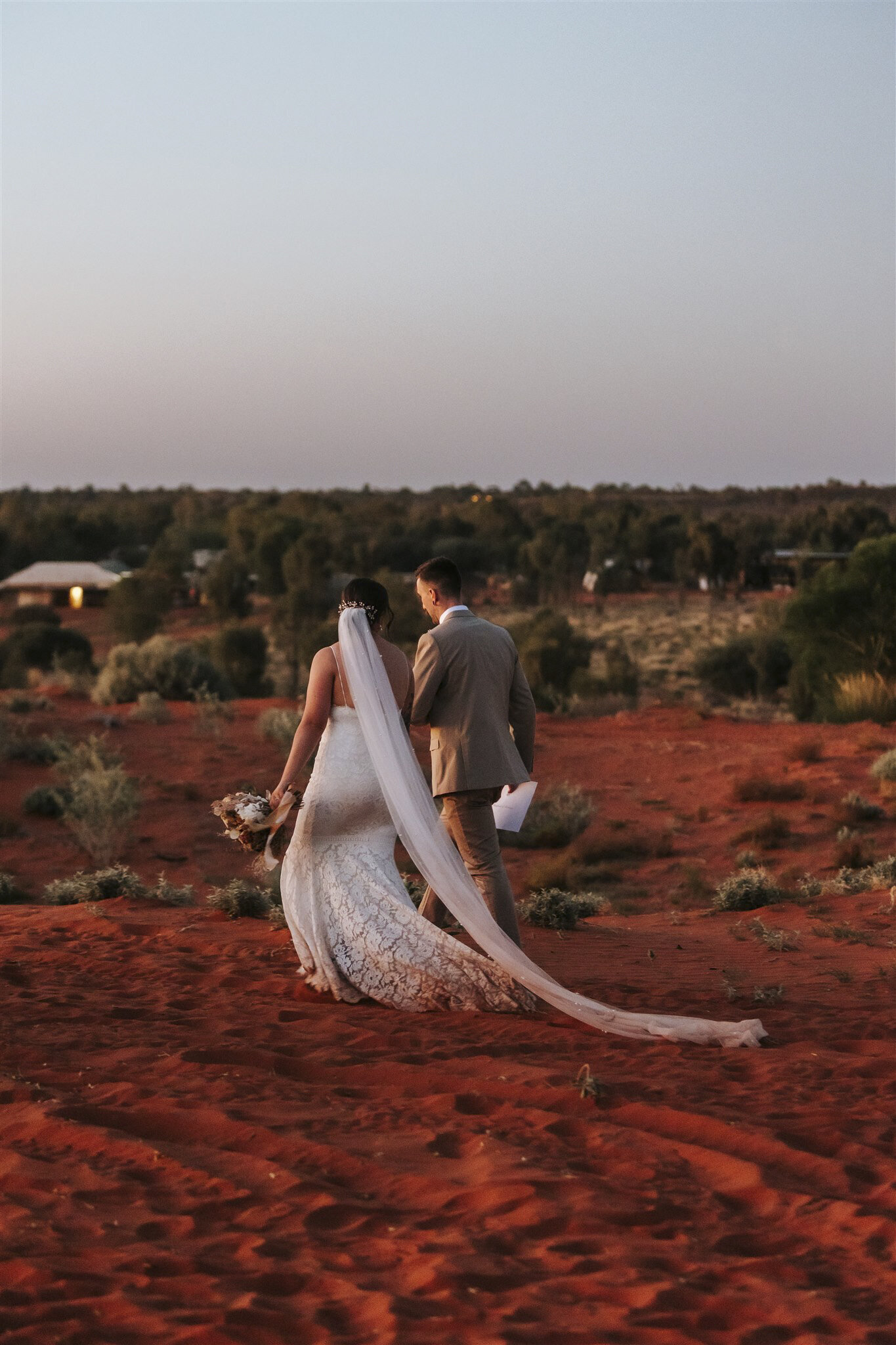 Bride and groom waling through the desert at their Uluru elopement