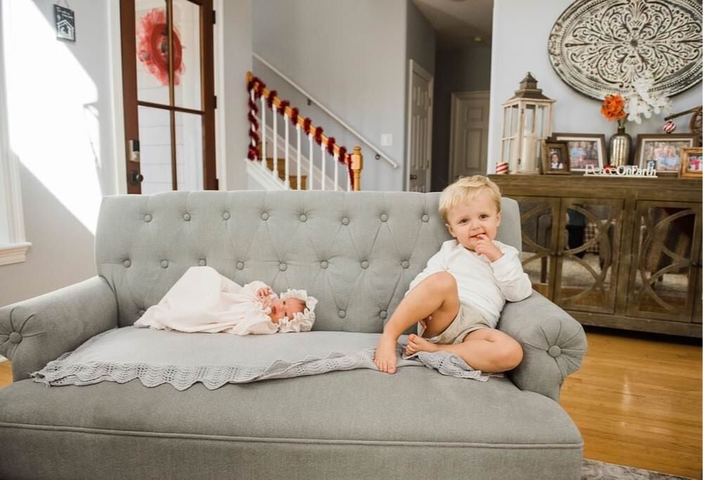 baby on sofa beside brother for newborn session