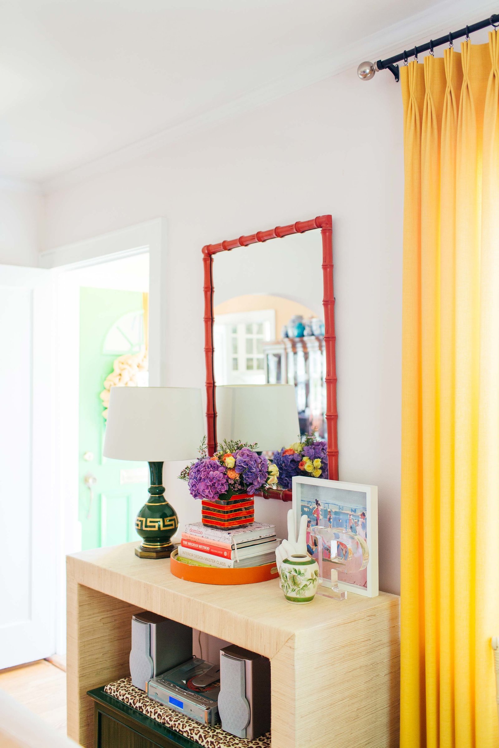 An entryway table with a lamp, mirror, and accessories.