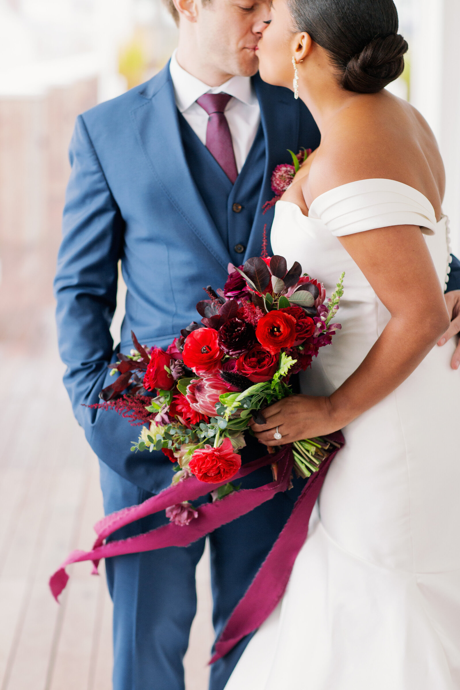 Couple kissing as one of them holds a large bouquet of flowers.