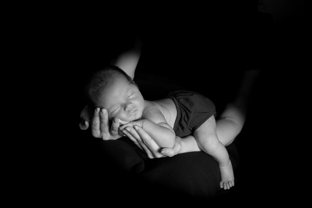Newborn Baby Boy in his mother's arms on black blanket created in studio Fort Mill SC