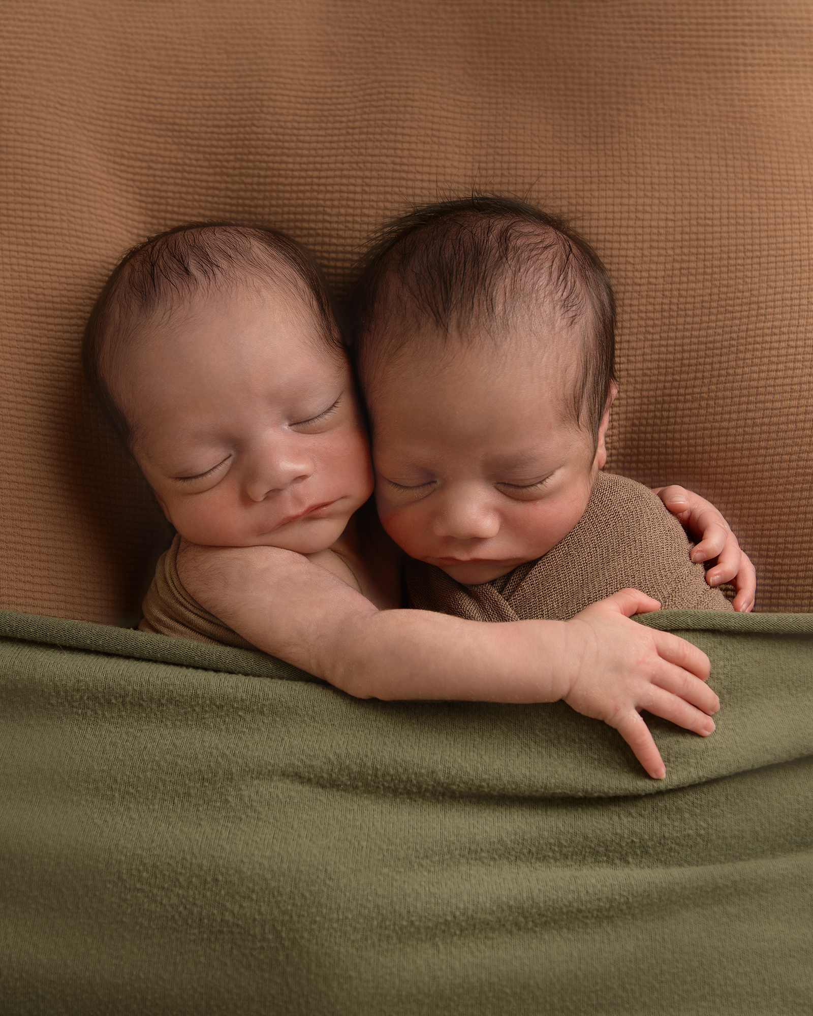 Newborn-twin-boys-in-cute-crib-and-clothes-embracing