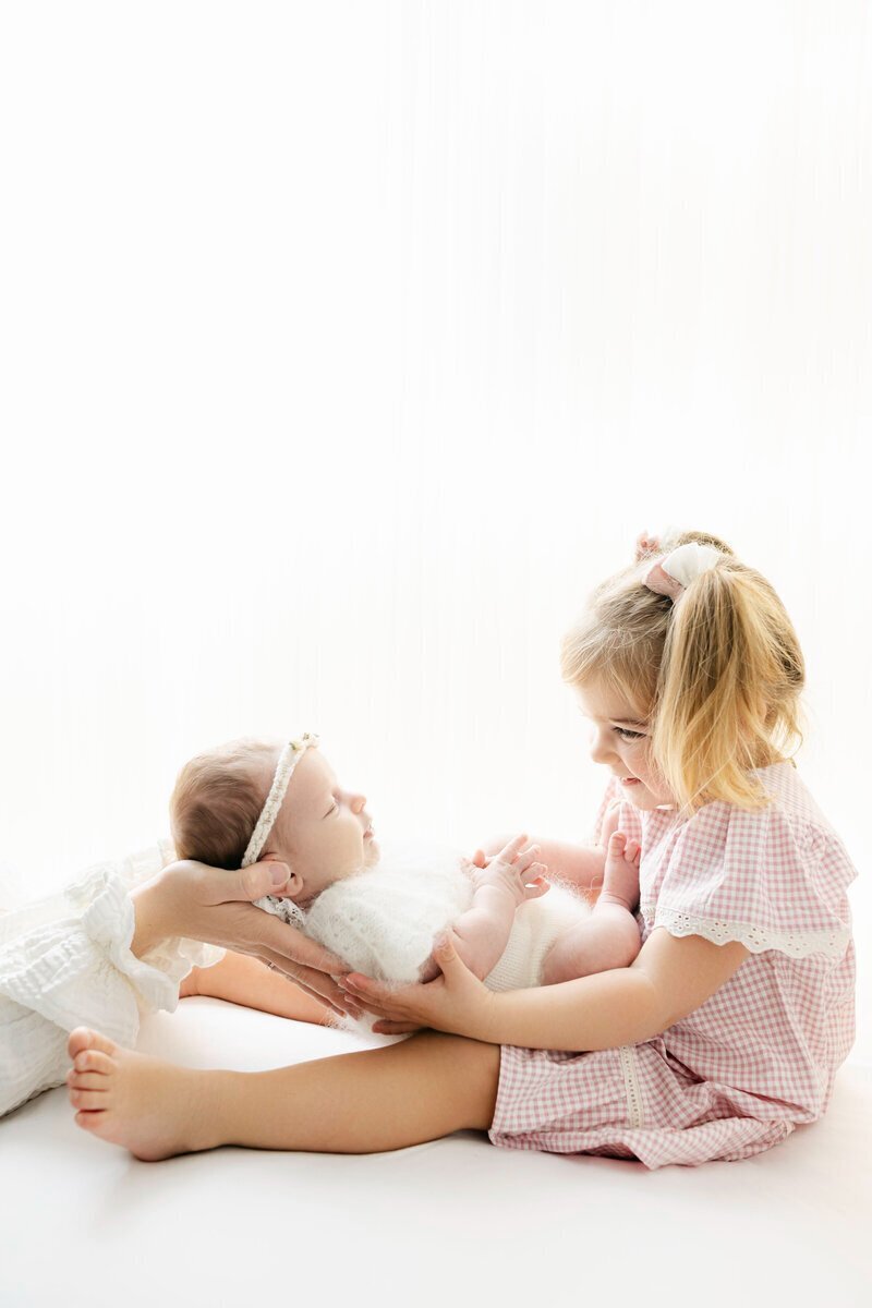 Little girl looking at her newborn baby sibling taken by new jersey newborn photographer, ally kimpton
