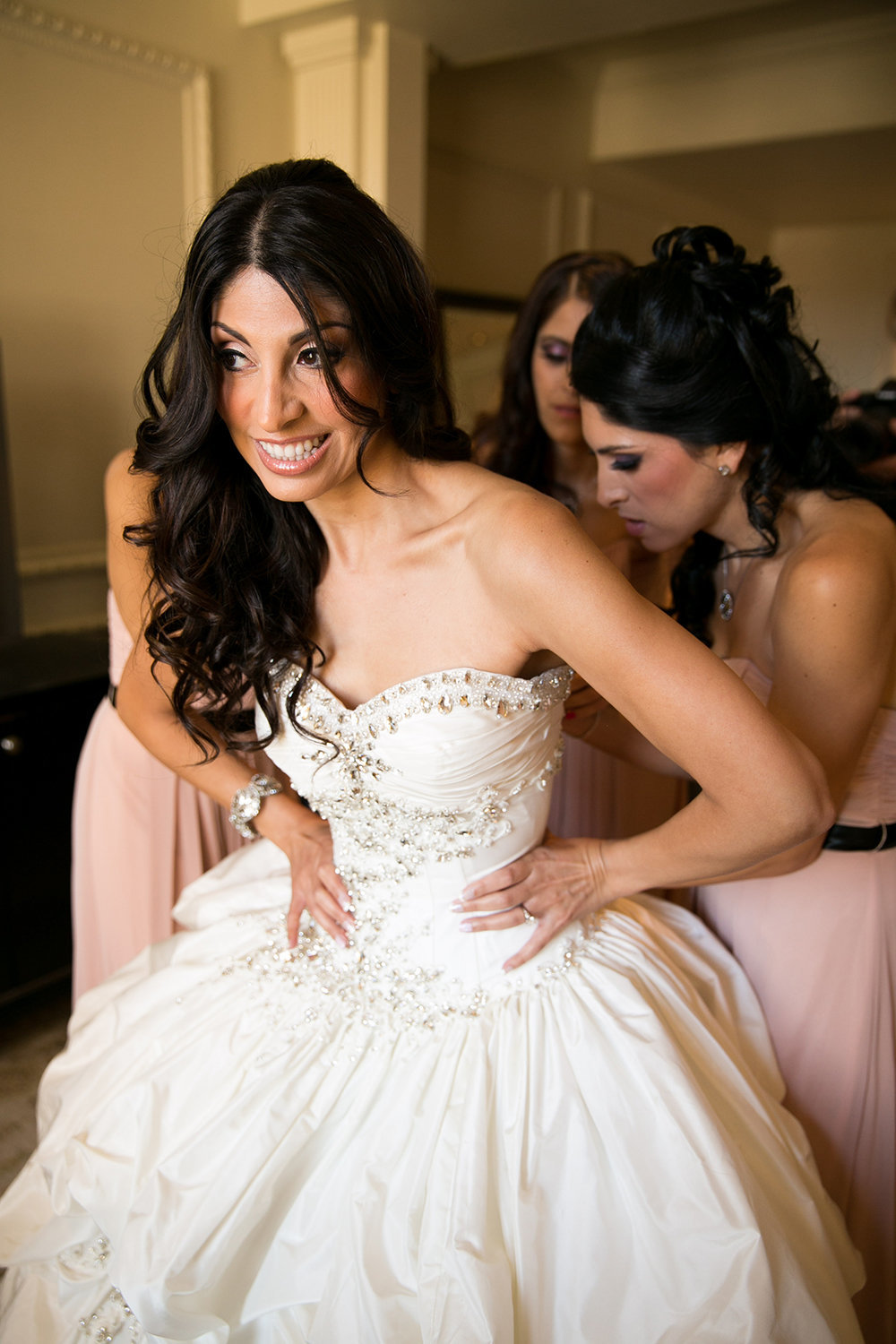 Bridesmaids help a very excited bride into her dress