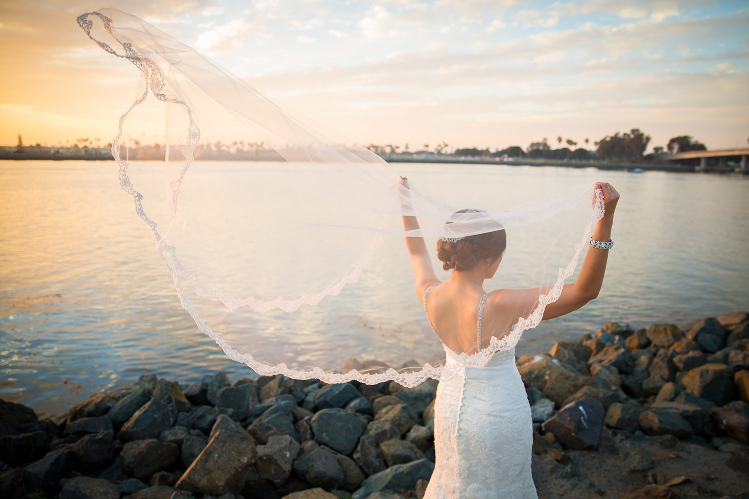 Bride's veil blowing in the wind with a beautiful Misison Bay sunset.