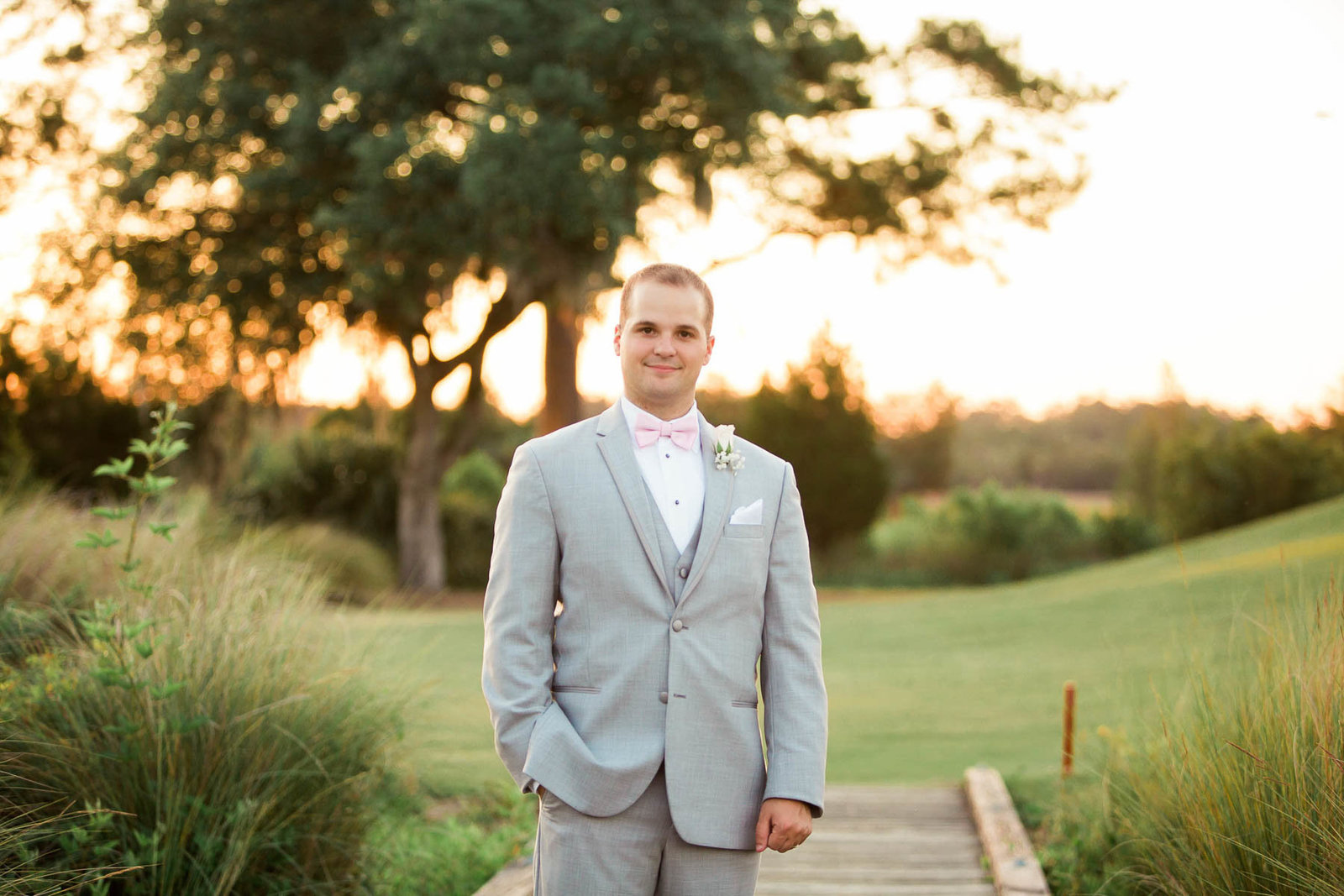 Groom stands in a field at sunset, Daniel Island Club, Charleston Wedding Photography.