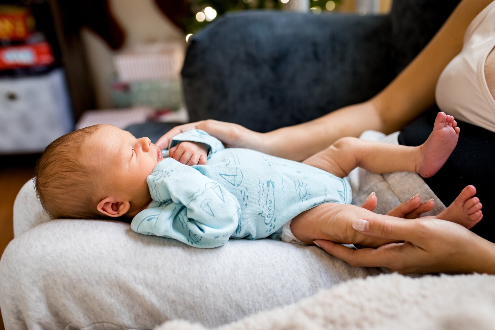 Mom holding newborn son in lap during in-home  newborn photo session.