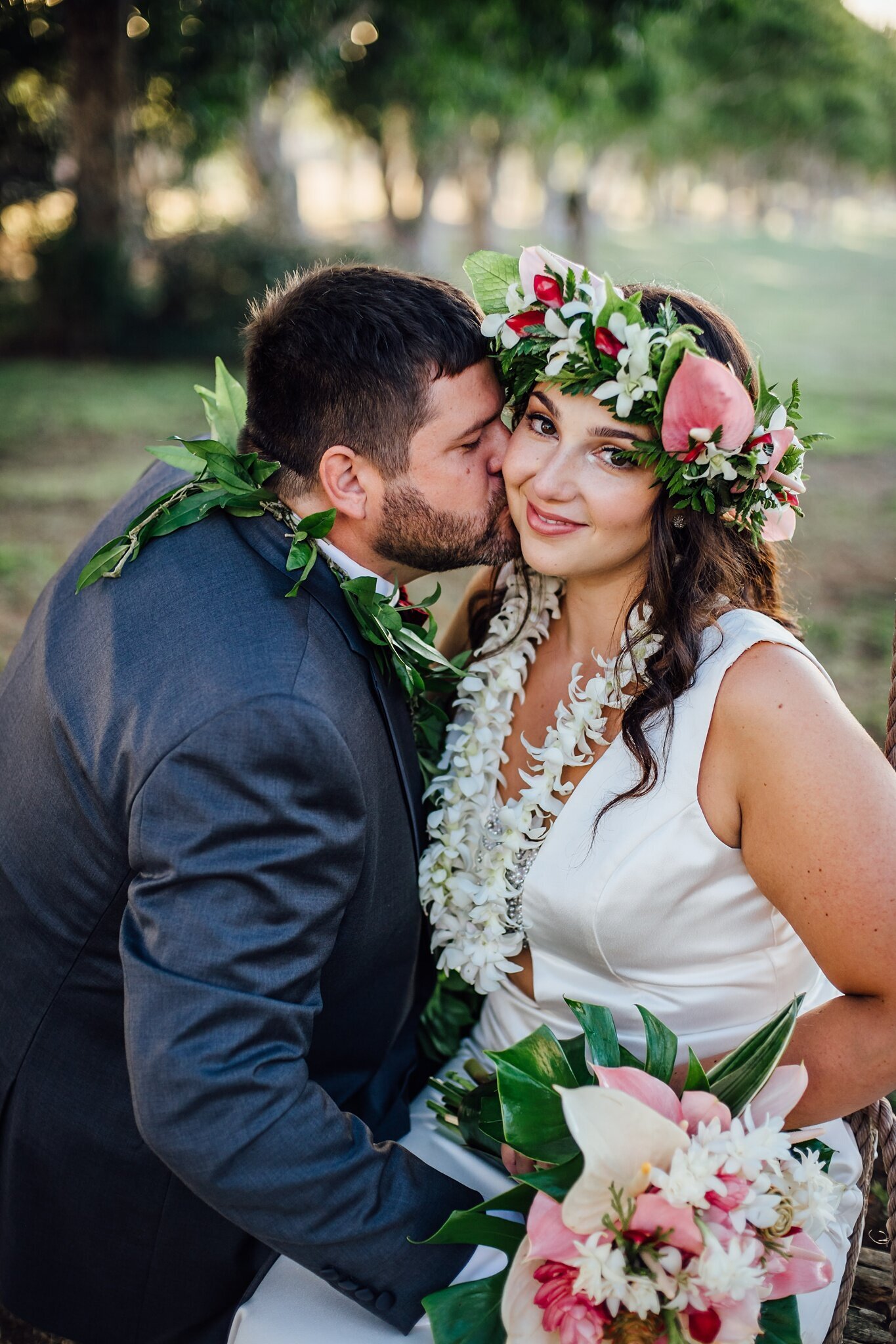 groom kissing bride on cheeks at their big island wedding