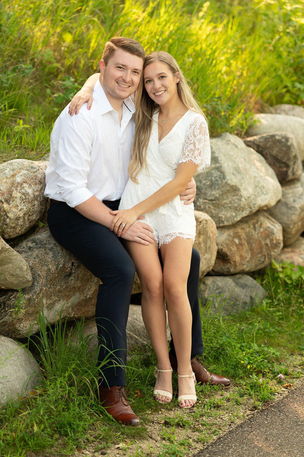 Man and woman dressed in white smile on rocks in Eagan, Minnesota.