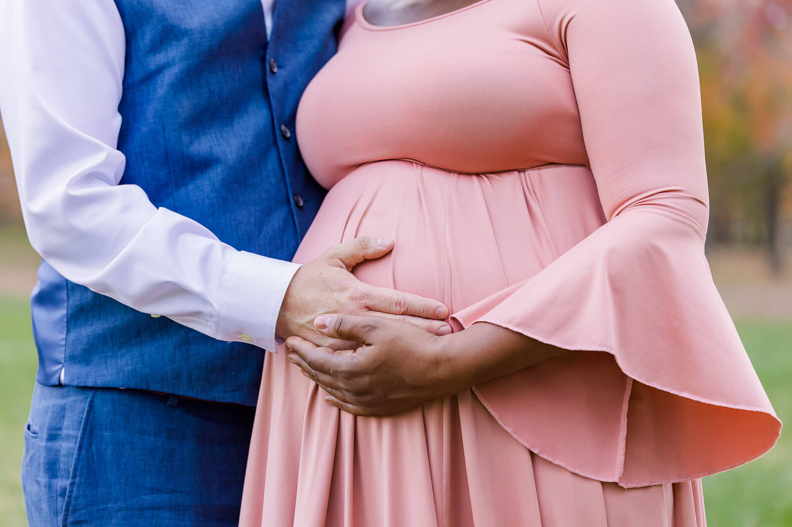 A close-up of a couple embracing her pregnant belly during their maternity session.