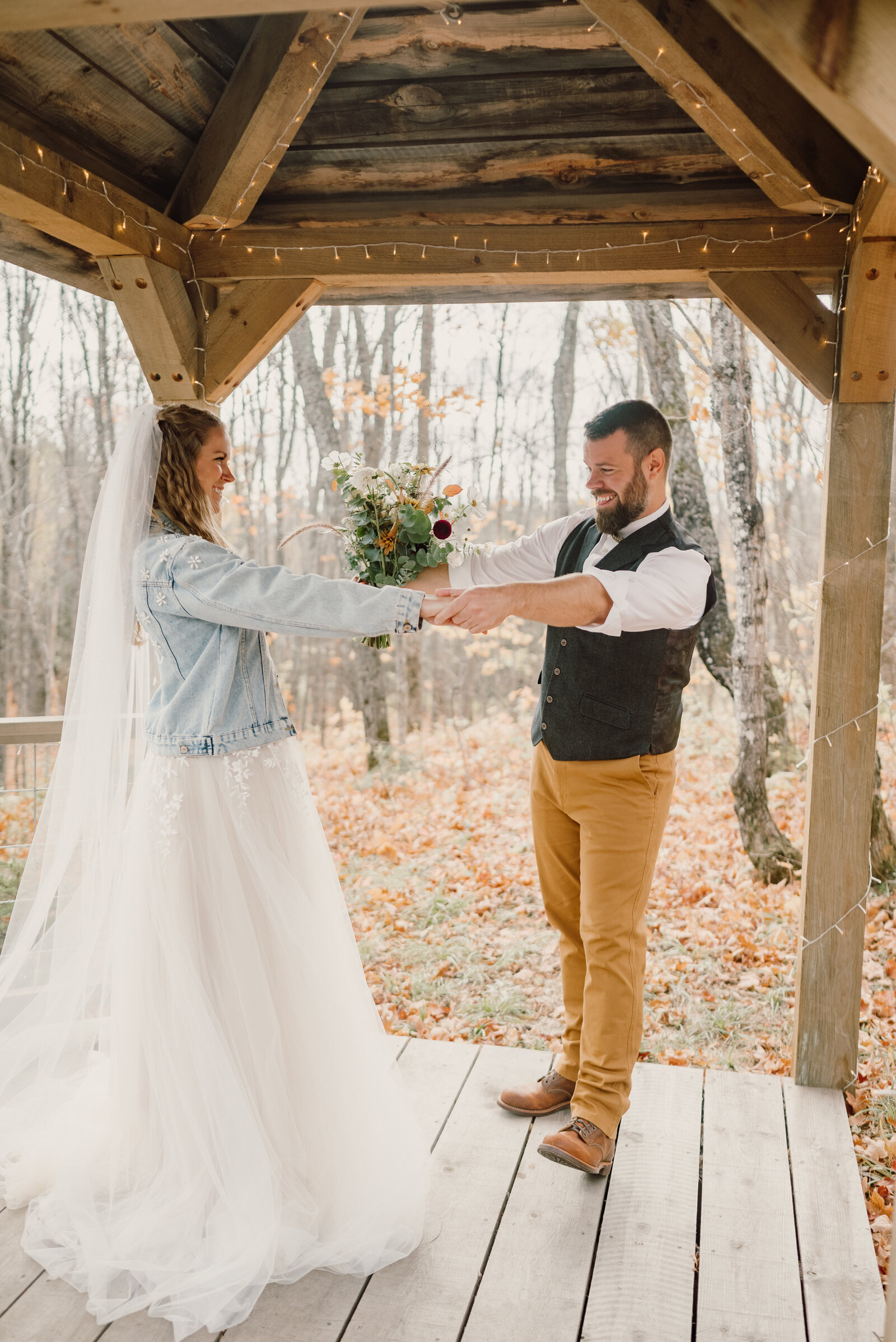 Groom hold bride's hands as he look around her bridal details