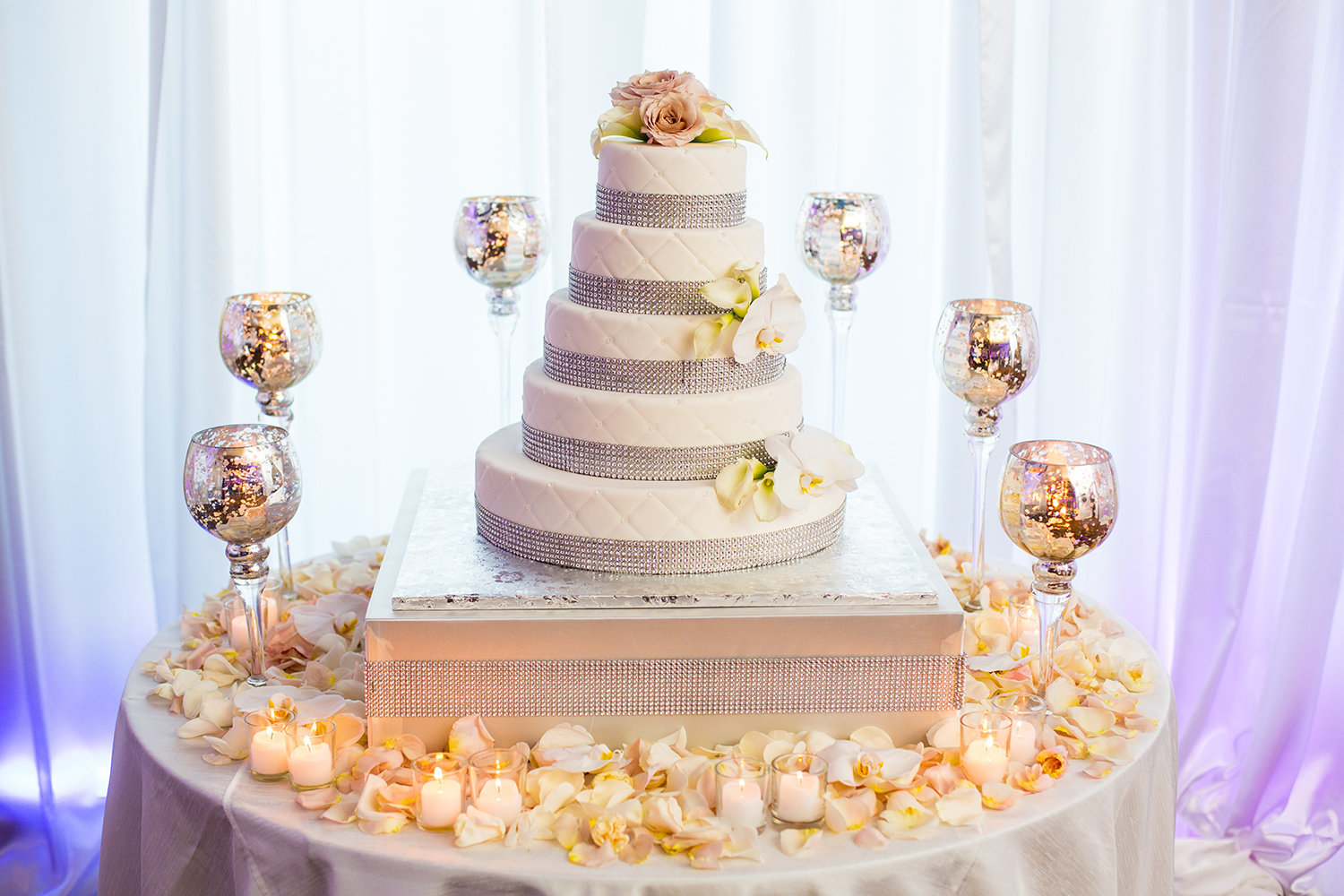 Wedding cake surrounded with candles and adorned with rose petals