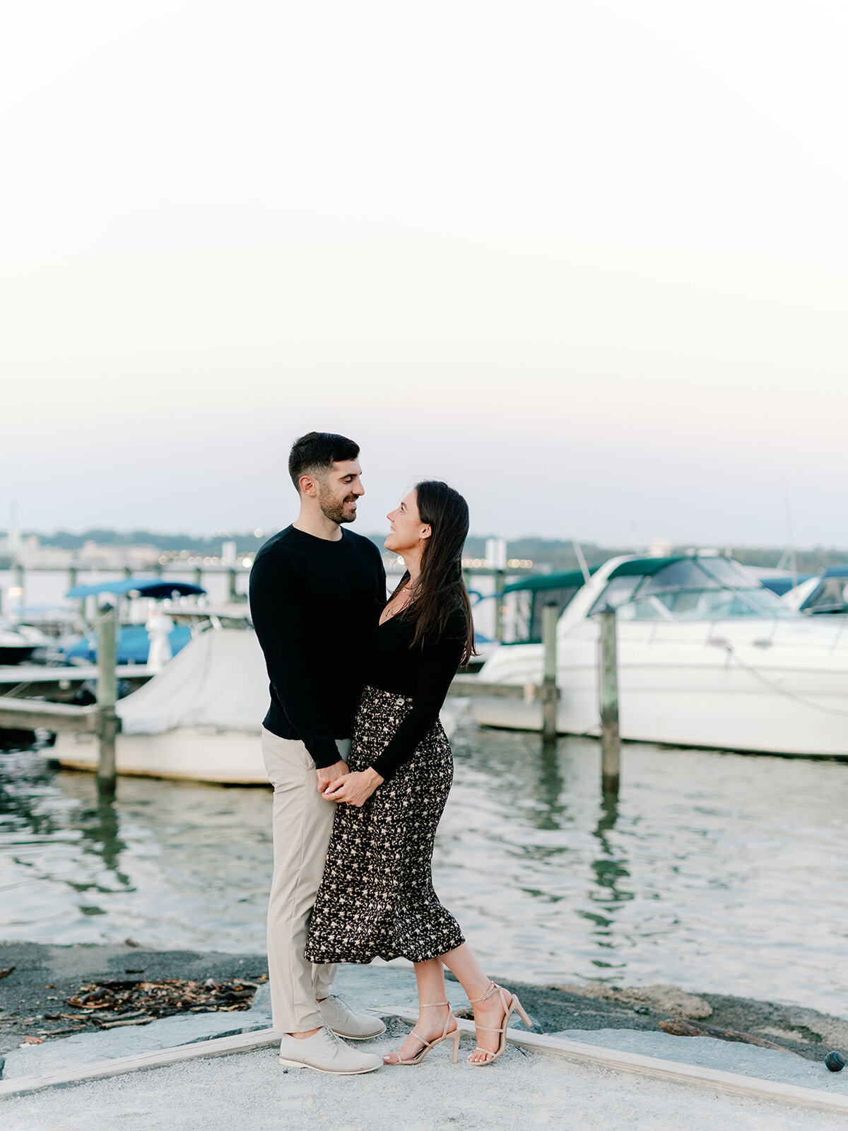 couple in front of the pier with boats in the background
