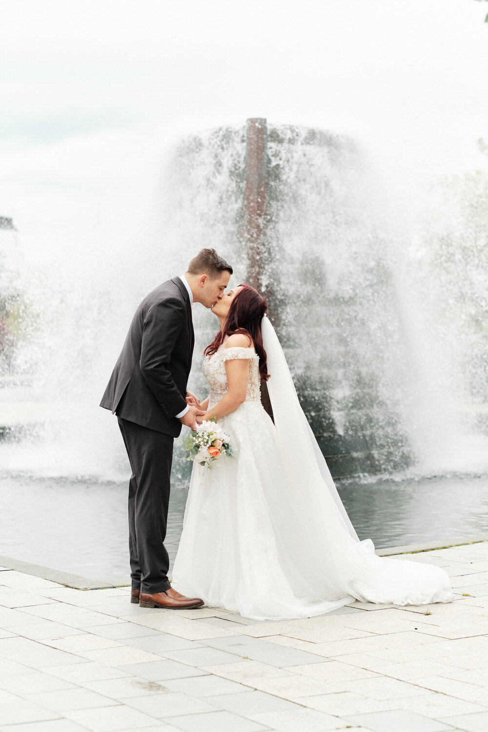 Bride and groom kiss as a waterfall goes off behind them