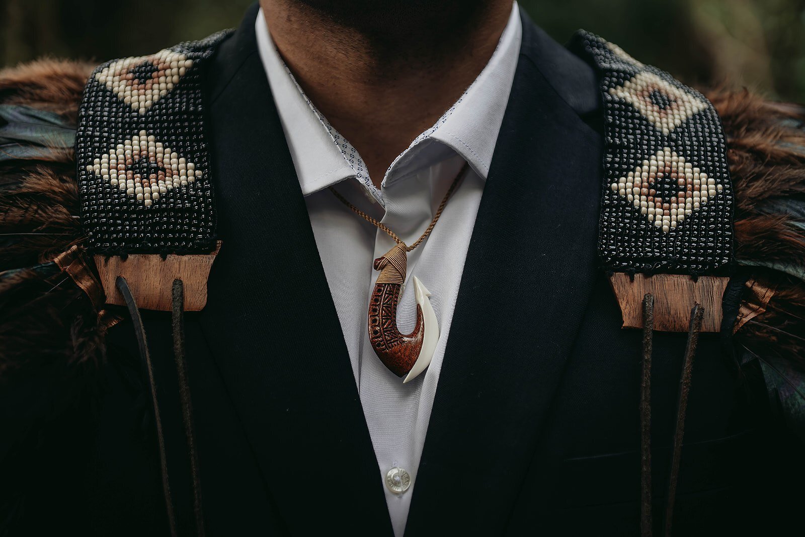 A person in a suit wears traditional Maori accessories and a carved pendant, embodying the creative spirit found at a photography retreat in New Zealand for creatives and connection.