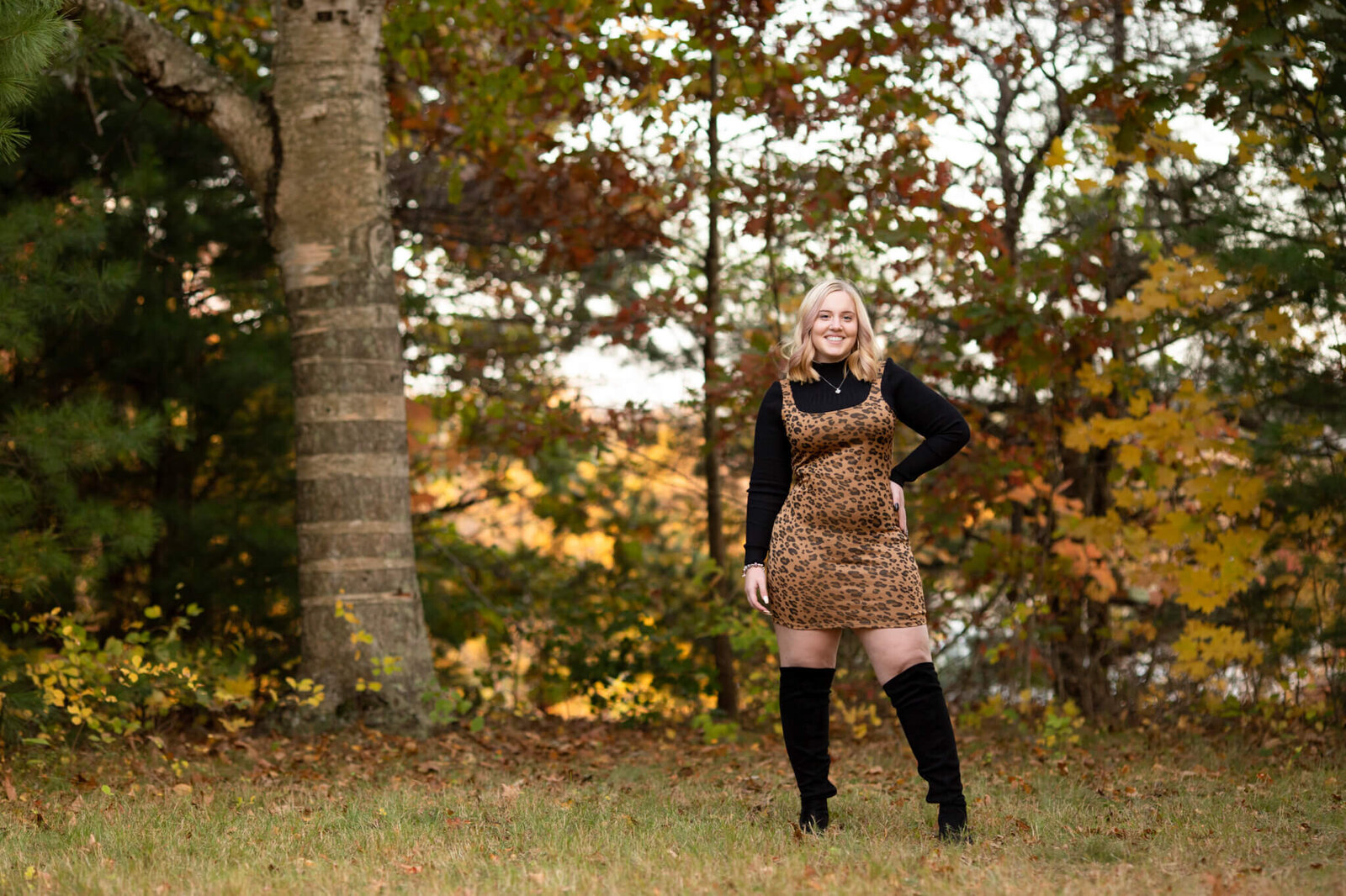 High school senior portrait of girl wearing leopard print dress  with woodland background