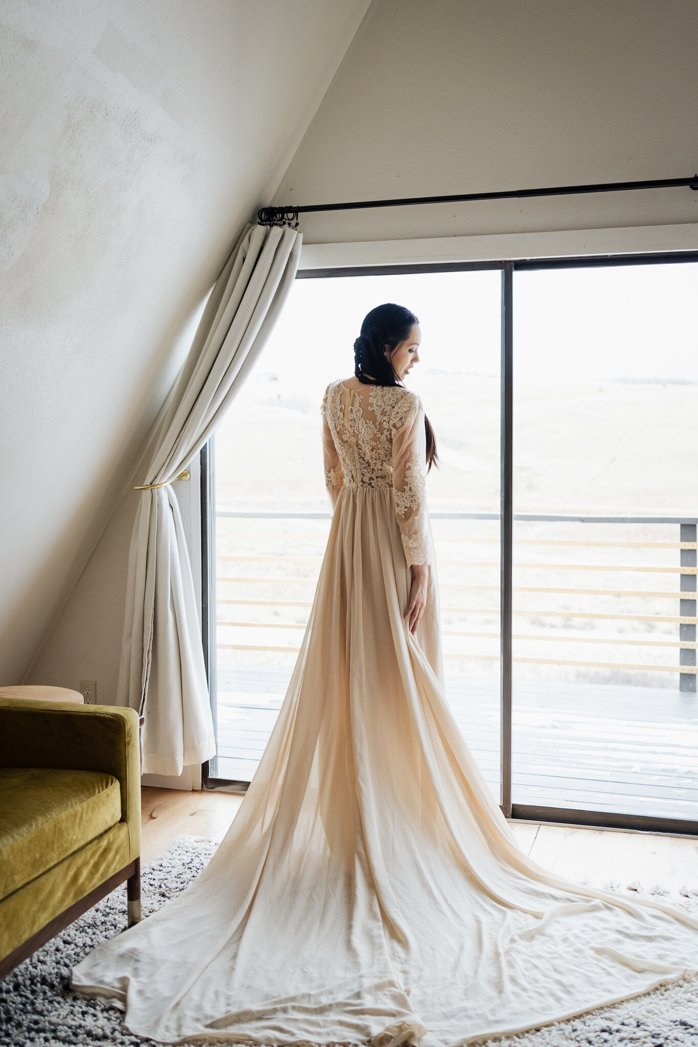 Bride looks out the window after changing into her wedding dress