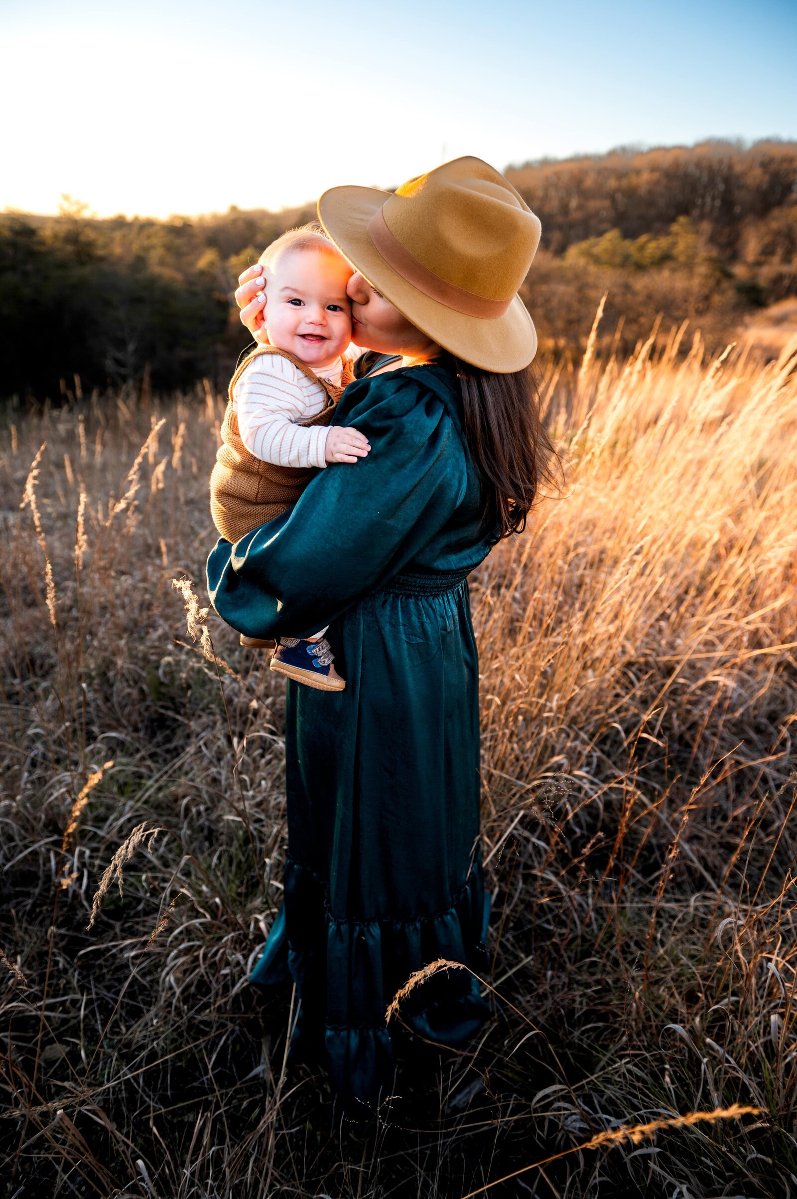 mom with a hat and green dress kissing her son