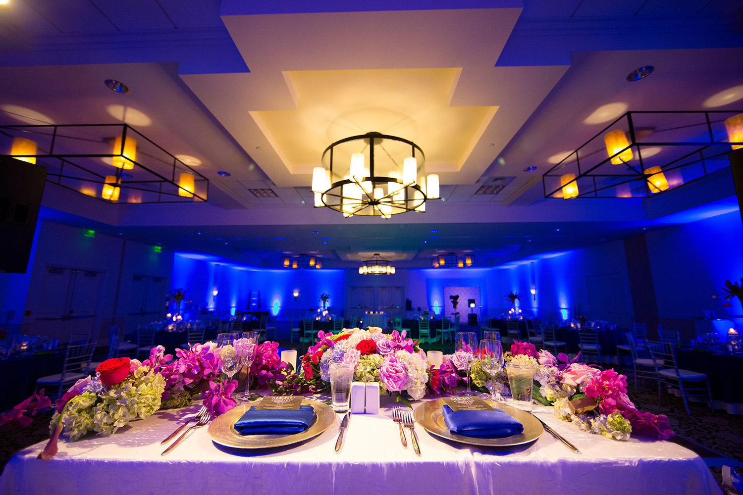 Indian weding reception head table with beautiful flowers and dramatic uplighting