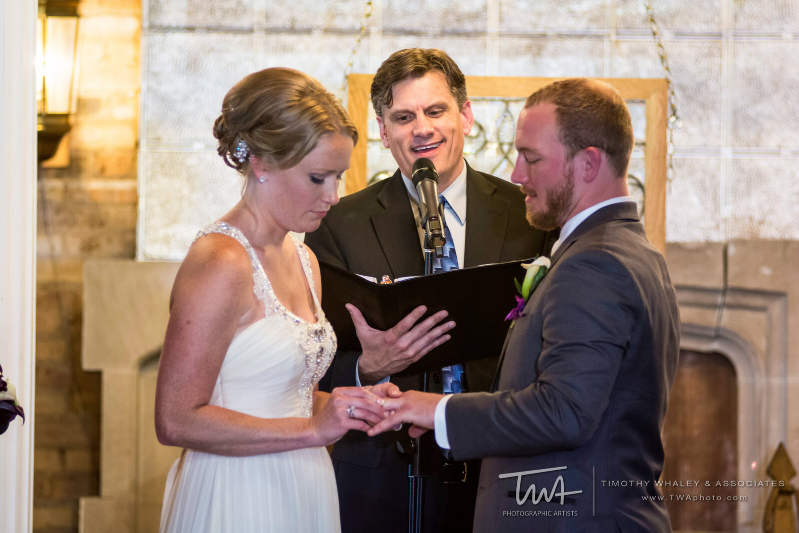 Bride slides wedding ring onto her groom's ring finger