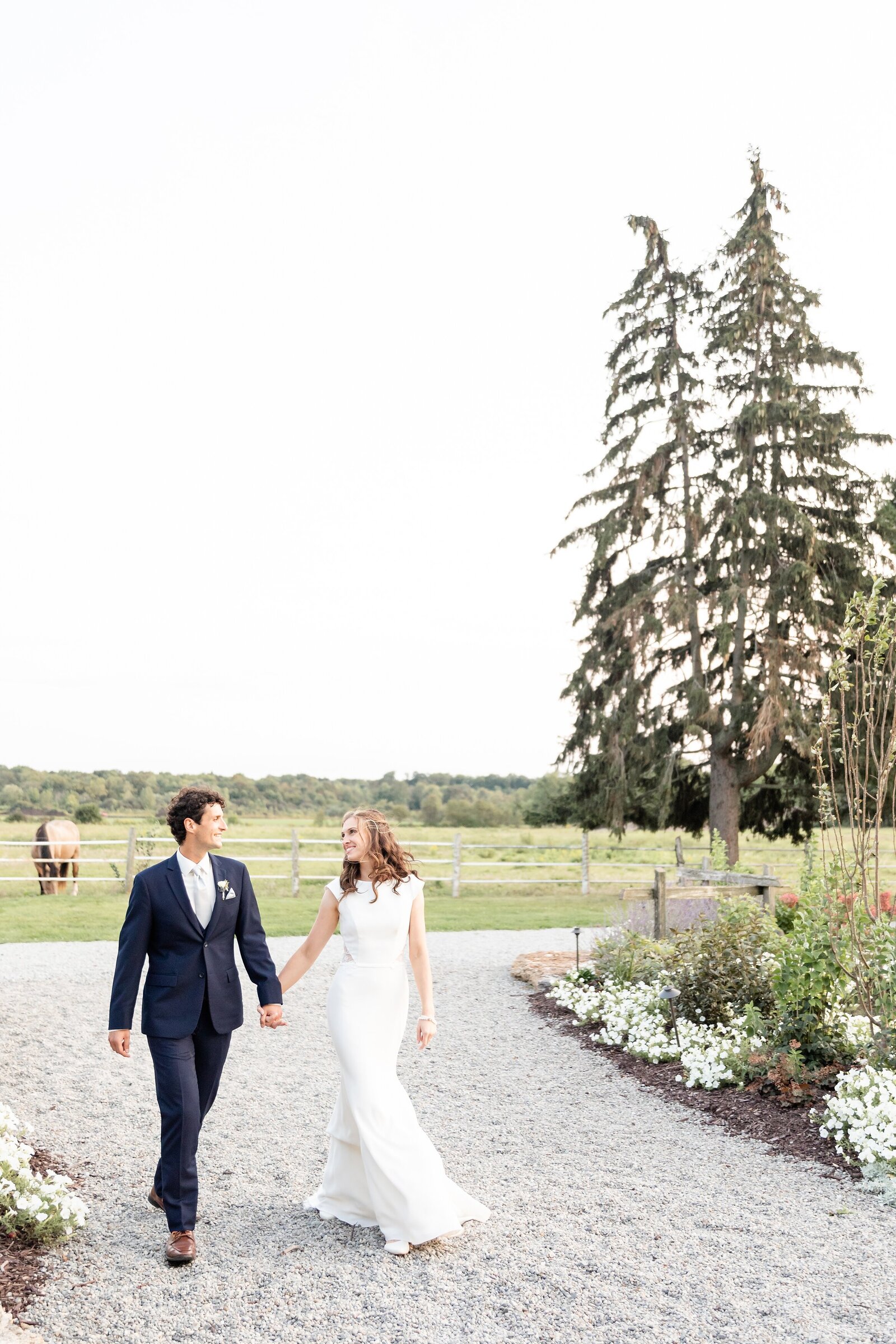 Newlyweds-walk-along-stone-pathway-during-sunset-at-a-maple-meadows-wedding