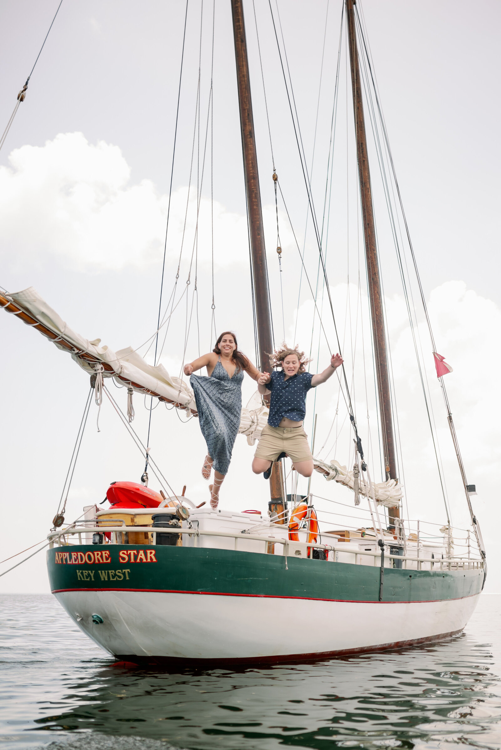 engaged couple jumping off the back of a sailboat into the water in Key West, Fl