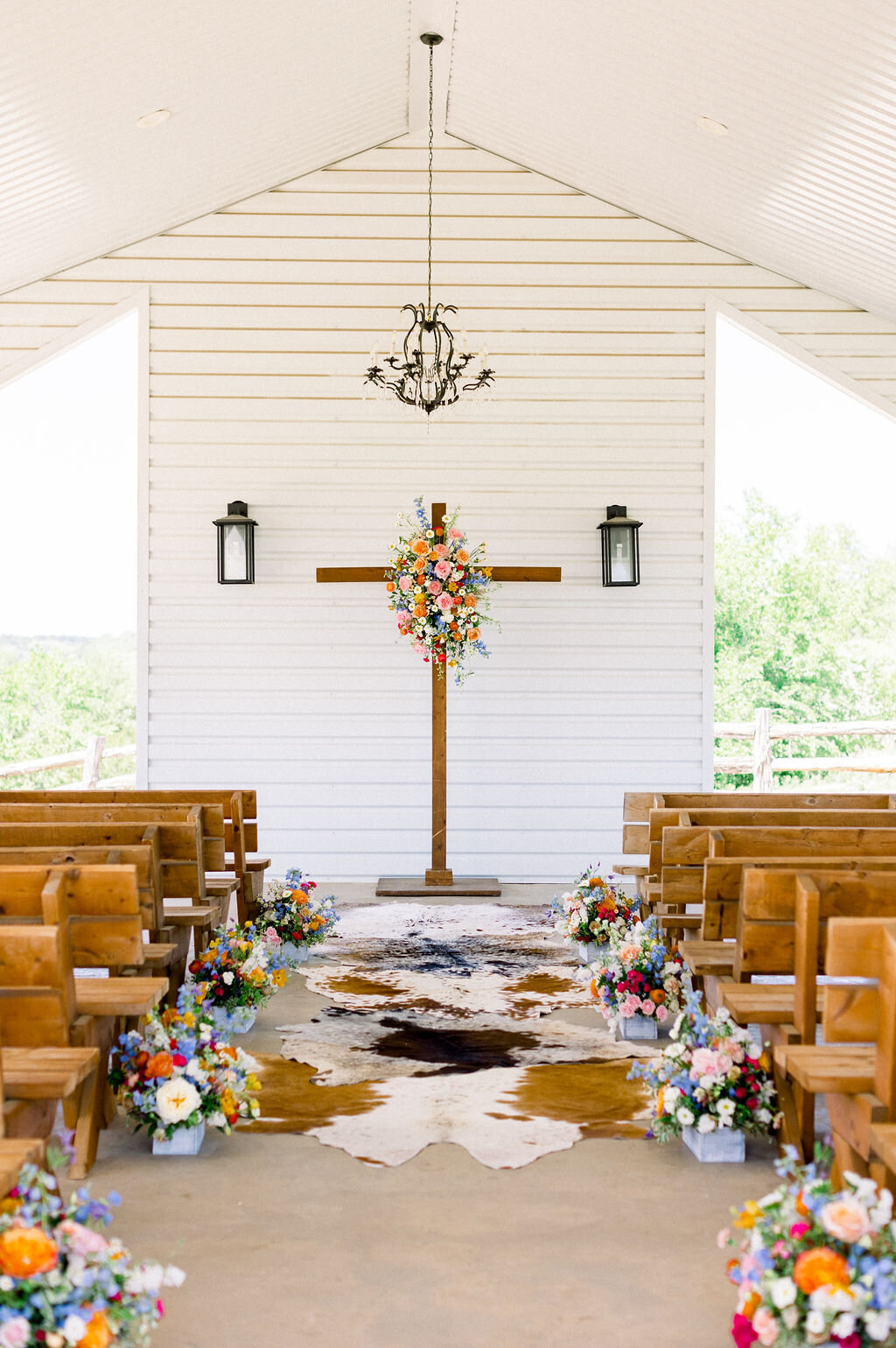 cowhide rug with bright flowers at ceremony alter