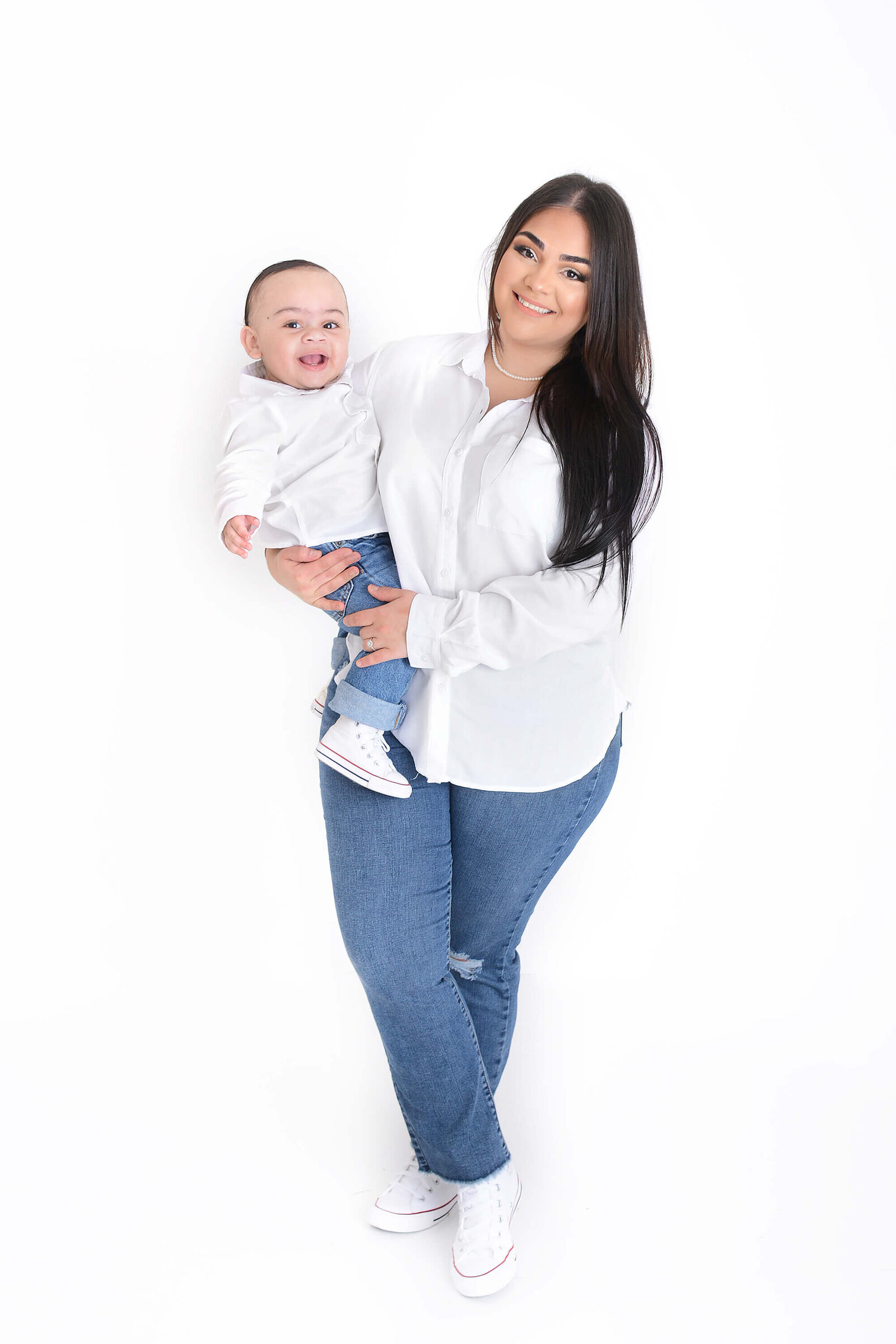 a mom holds her baby boy in front of a white background