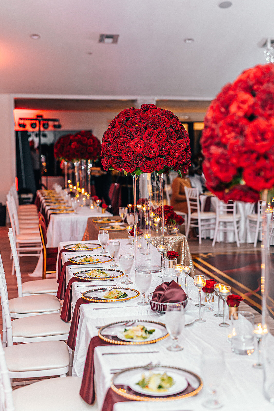 Wedding reception table settings with red roses and candles