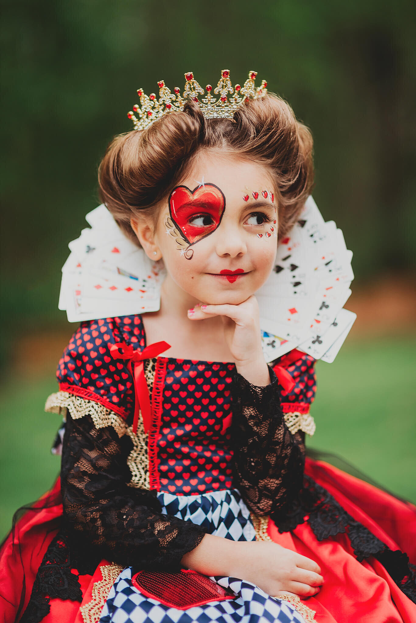 Girl with crown in a red queen dress with face makeup