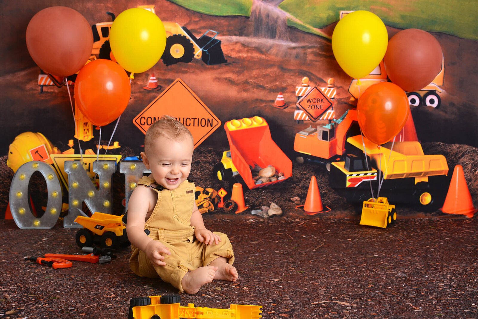 boy smiles at his construction themed first birthday photoshoot