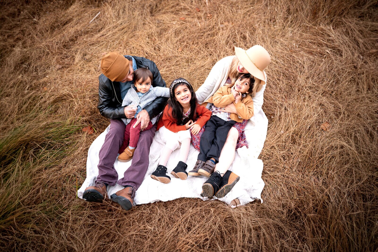 family laying in a grass field on a blanet