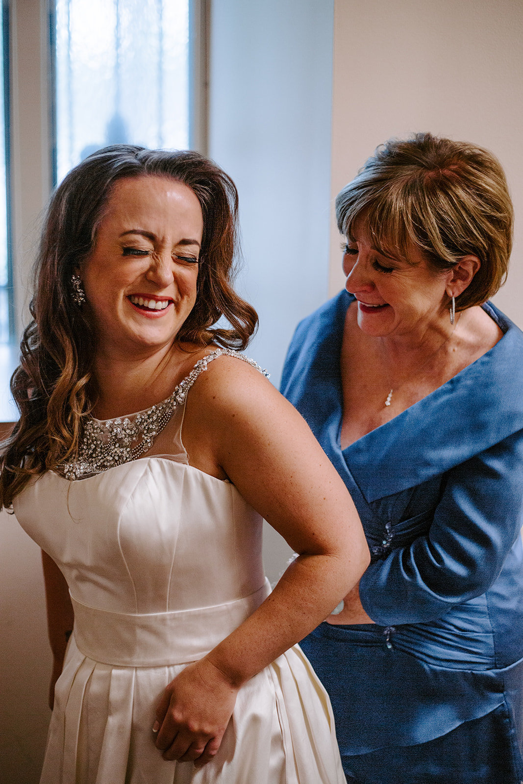 Mom helping her daughter put on her wedding dress during her Minneapolis Wedding day