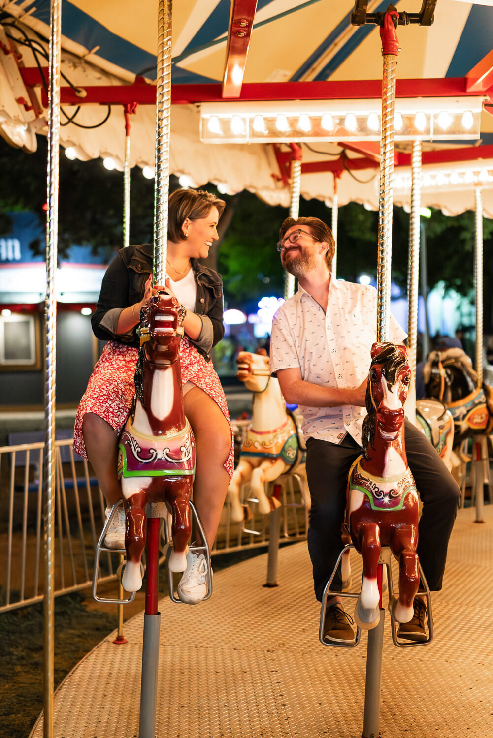 Man and woman ride the carousel at the Minnesota State Fair at night.